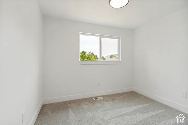 Bright 3rd bedroom featuring a window with white trim, light gray carpet, white walls, and a flush-mount ceiling light