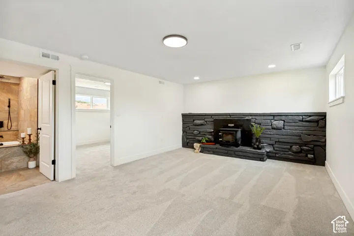 Spacious flex/family room featuring light-toned carpet flooring and a prominent black stone fireplace with an integrated wood stove.