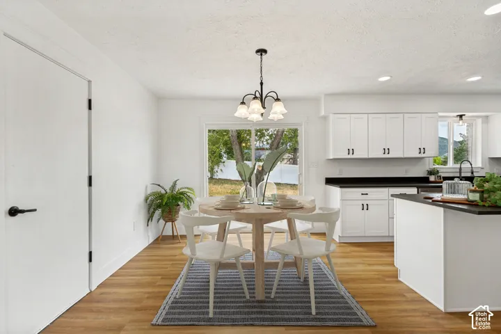 Dining area featuring LVP flooring, a contemporary chandelier, and a large window overlooking the exterior