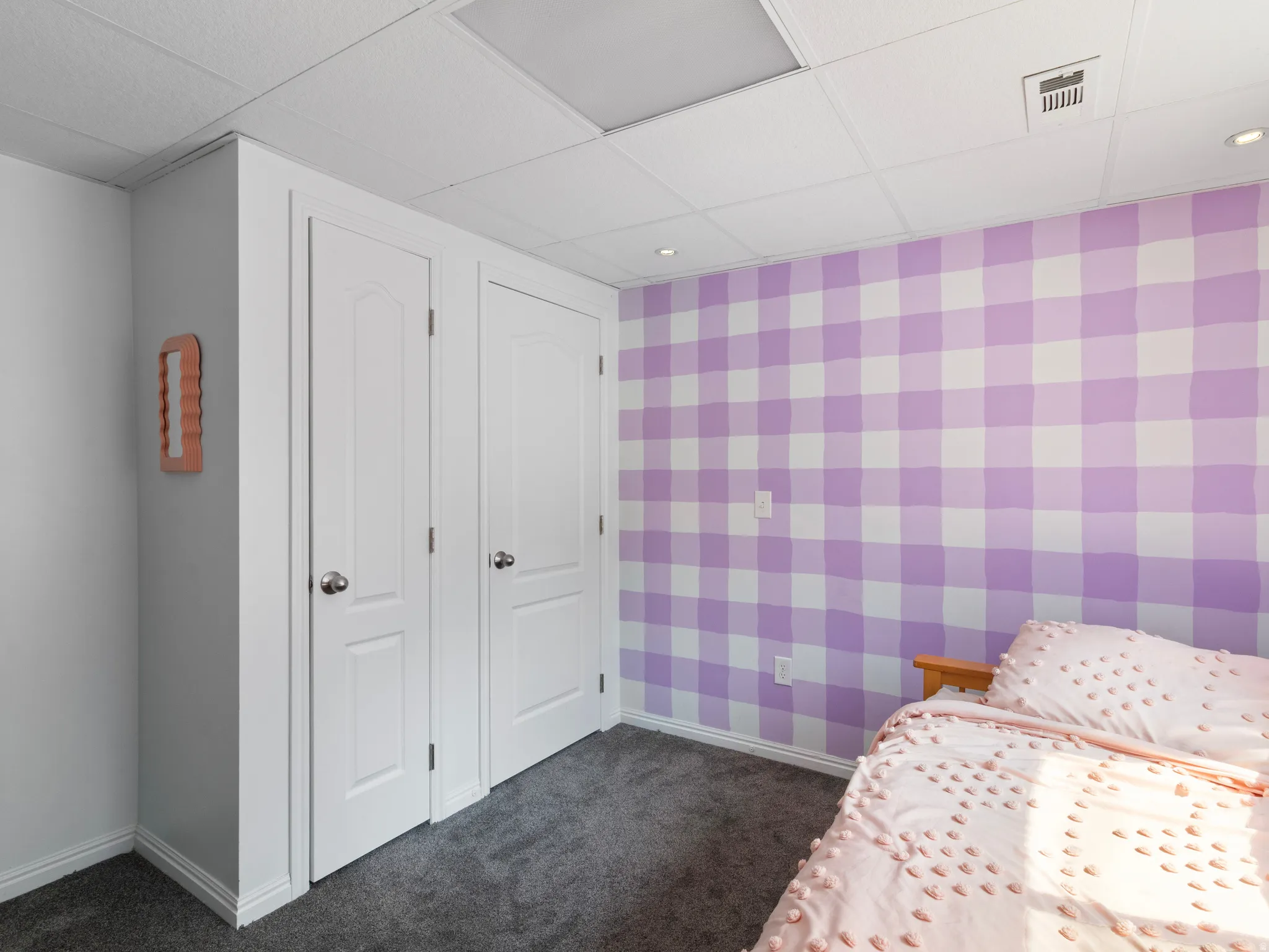 Room featuring a drop ceiling with recessed lighting, two white panel doors, and a patterned accent wall