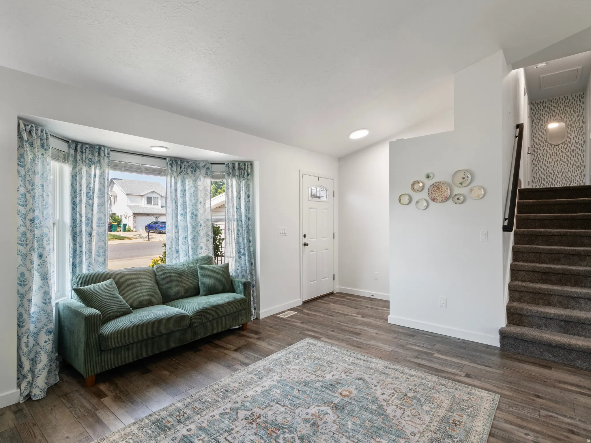 Bay window with natural light, wood-finish flooring, recessed lighting, and a front entry door with decorative glass