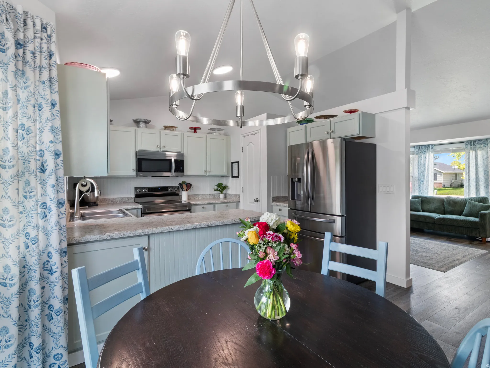 Kitchen with light-toned cabinetry, stainless steel appliances, and a central island with beadboard detailing
