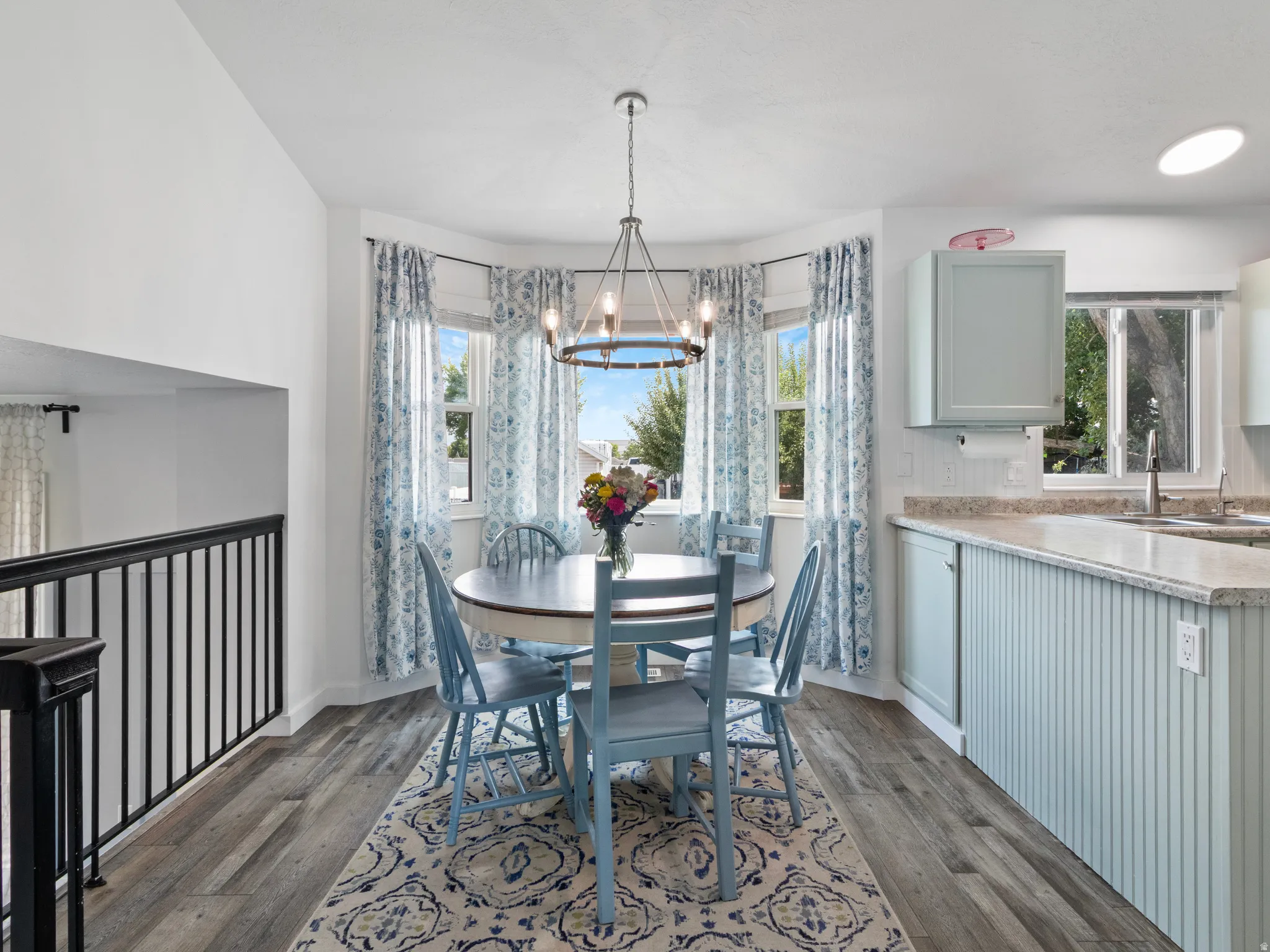 Dining area featuring a bay window with multiple panes, wood-finish flooring, and a contemporary chandelier