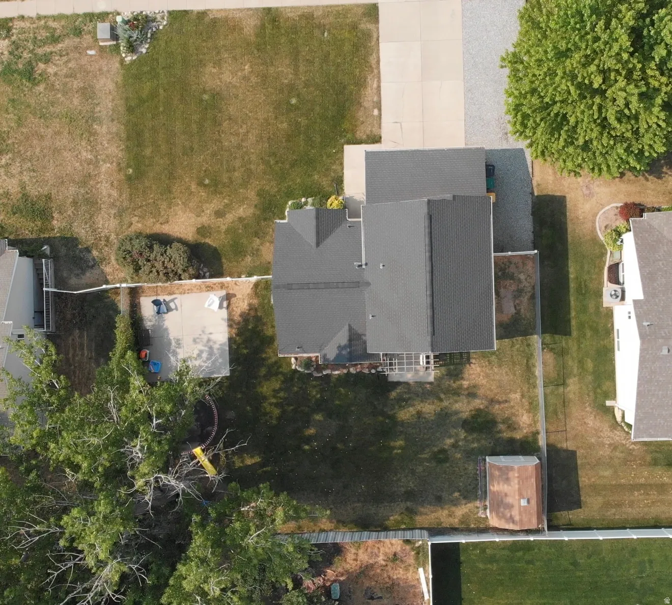 Property featuring a dark shingle roof, a concrete driveway, and a detached storage shed