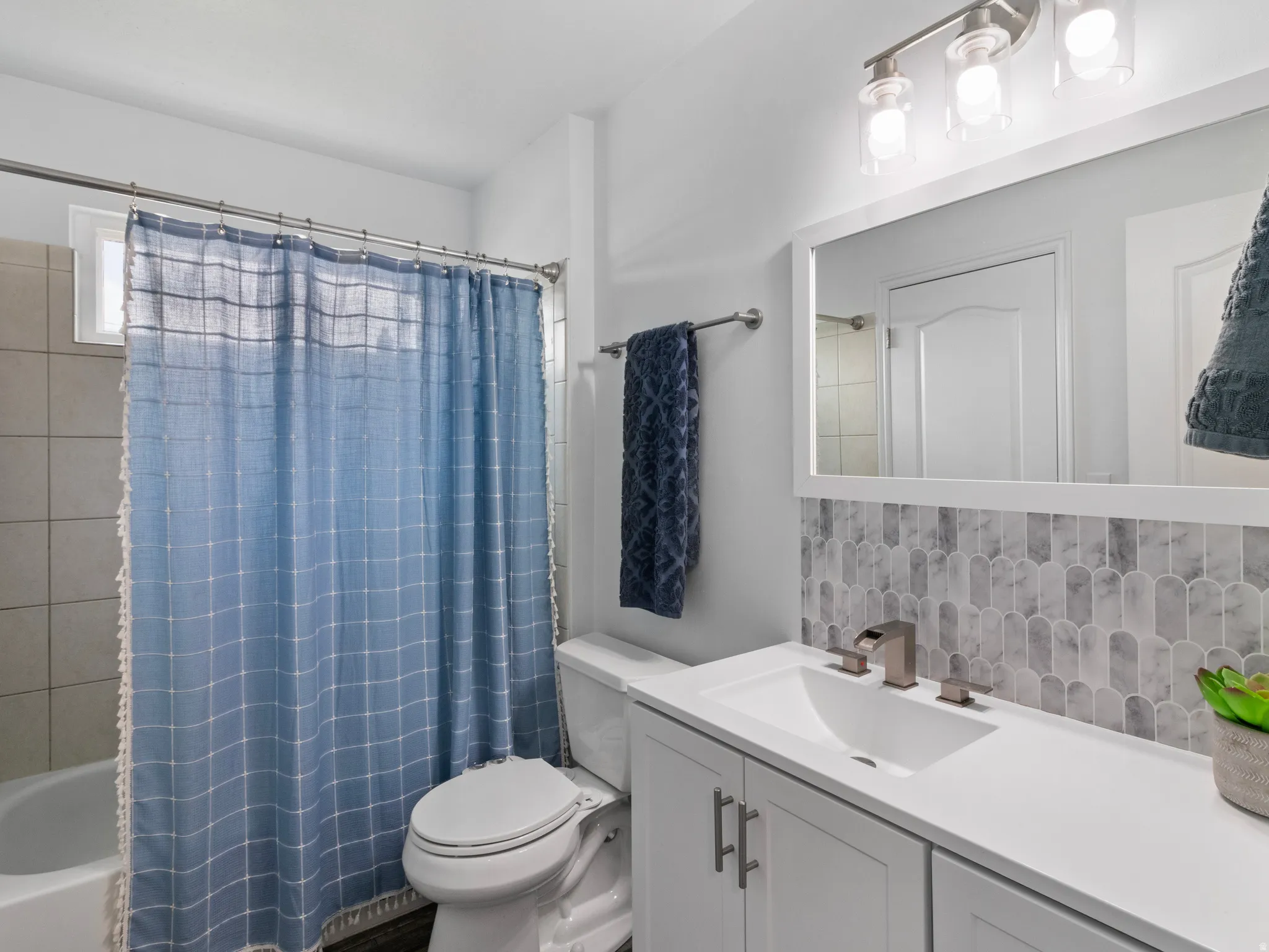 Bathroom featuring a white vanity with an integrated sink, brushed nickel faucet, and a patterned tile backsplash