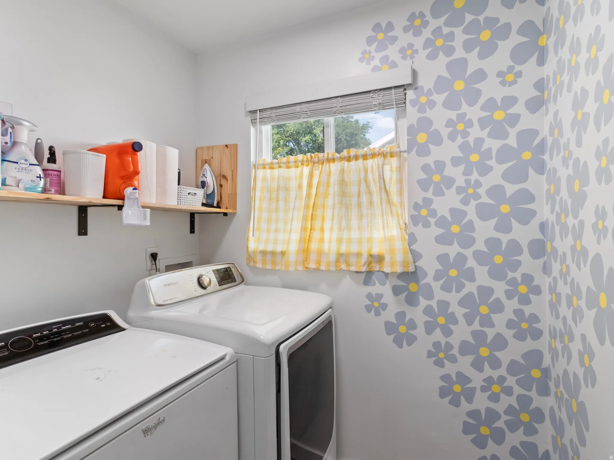 Dedicated laundry space featuring a window, built-in shelving, two appliances, and decorative wall accents