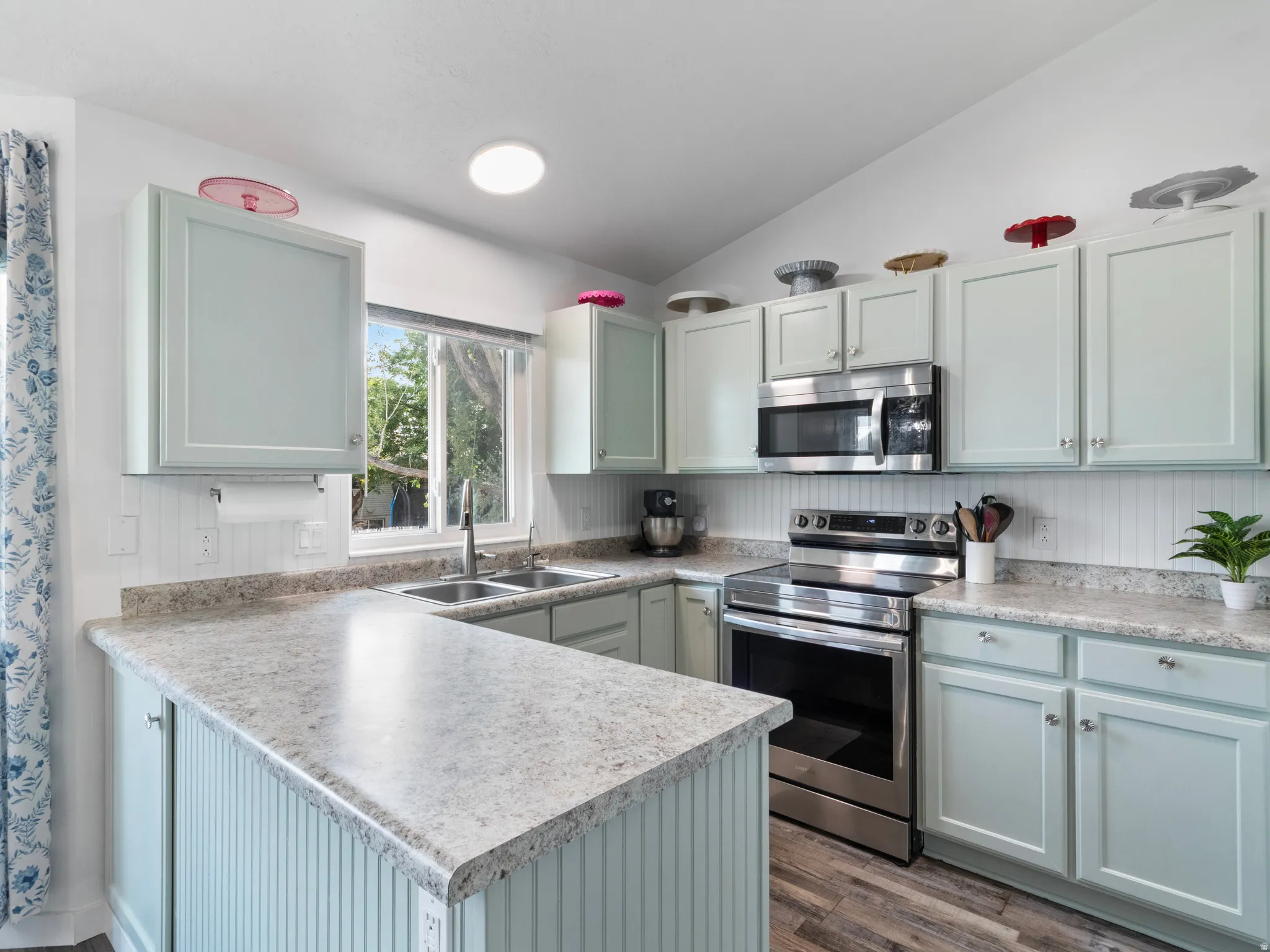 Kitchen featuring light blue cabinetry, stone-finish countertops, stainless steel appliances, and wood-finish flooring