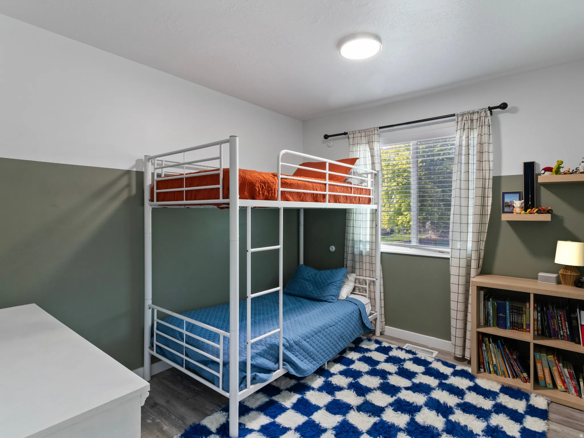 Bedroom featuring a window with blinds, wood-finish flooring, a flush-mount ceiling light, and two-tone wall paint