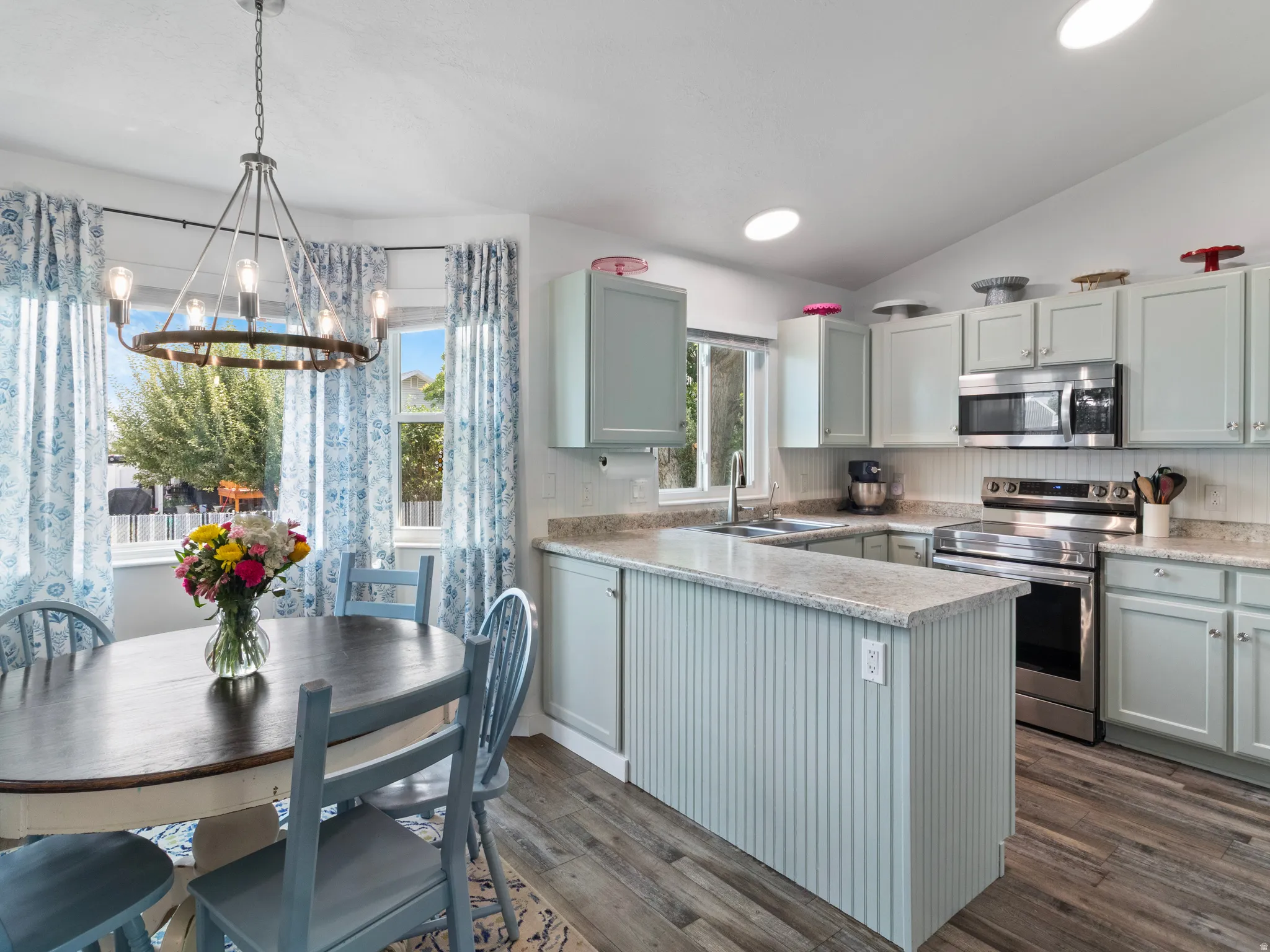 Kitchen featuring light-toned cabinetry, stainless steel appliances, and a central island with beadboard paneling