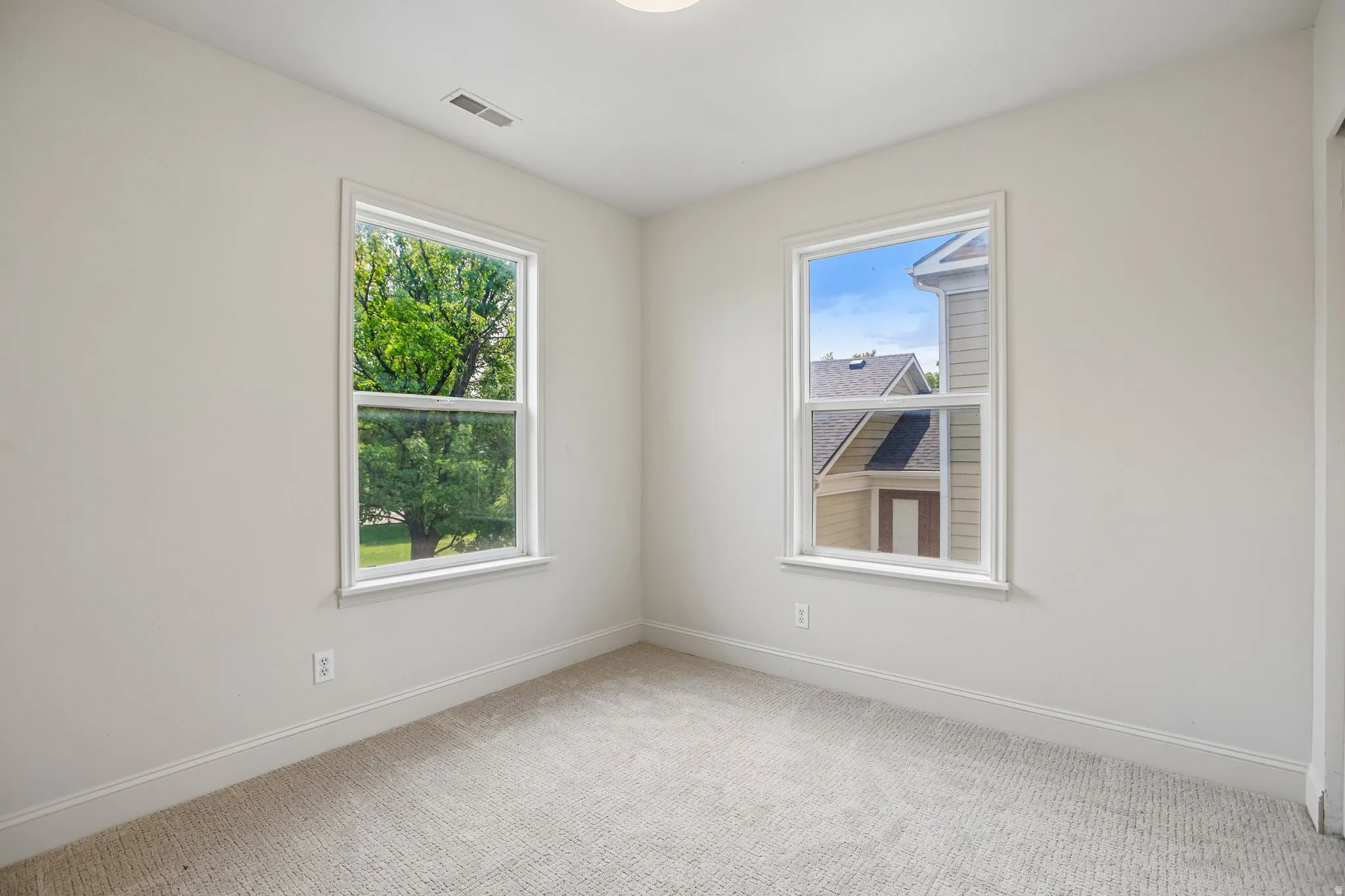 Room featuring light-colored carpeting, white walls, and two large windows with white trim