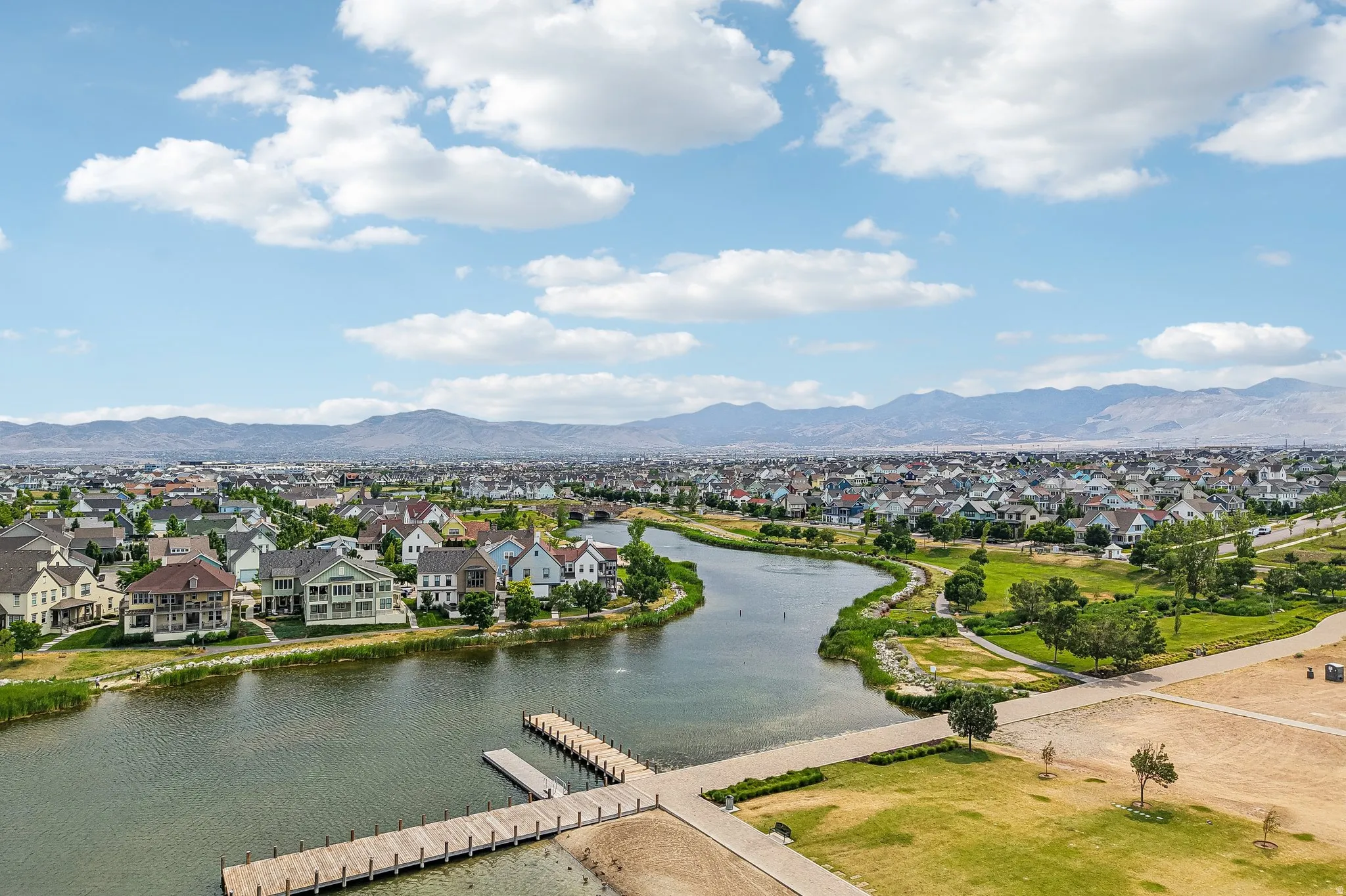 A residential community featuring a winding waterway with multiple docks and surrounding green spaces, set against a distant mountain range