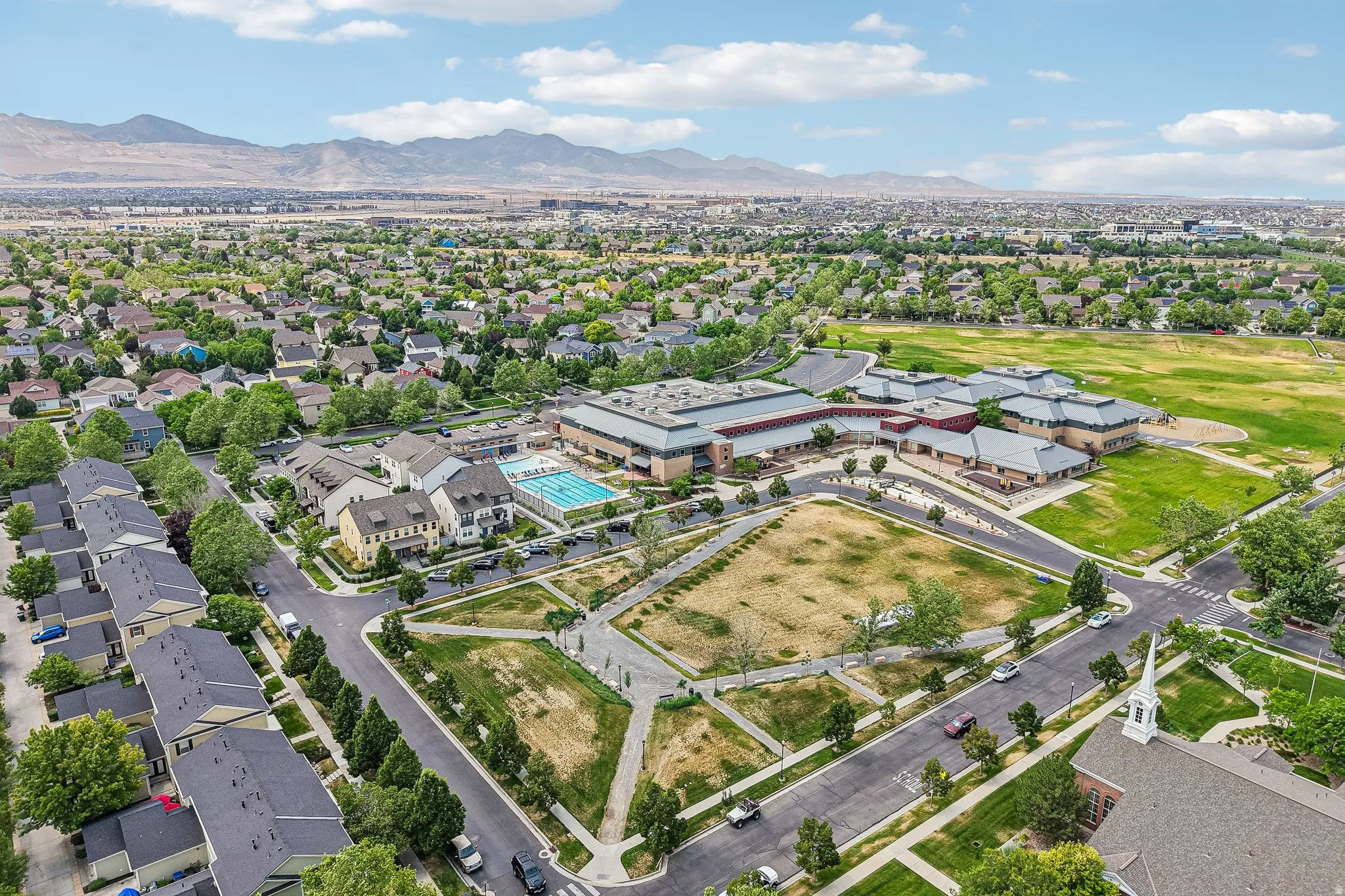 Expansive residential area featuring numerous single-family homes, townhomes, and a large institutional building with athletic fields