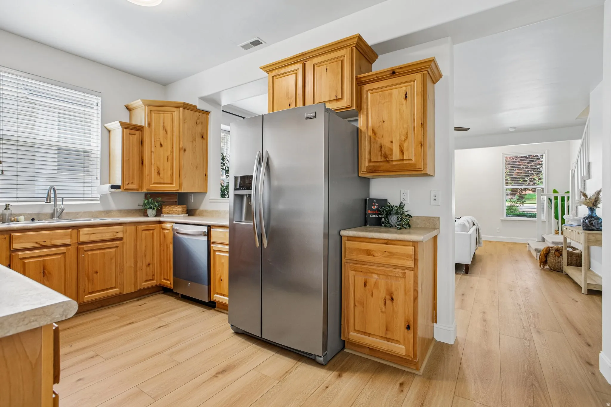 Kitchen featuring light wood-finish flooring, stainless steel refrigerator, and integrated dishwasher