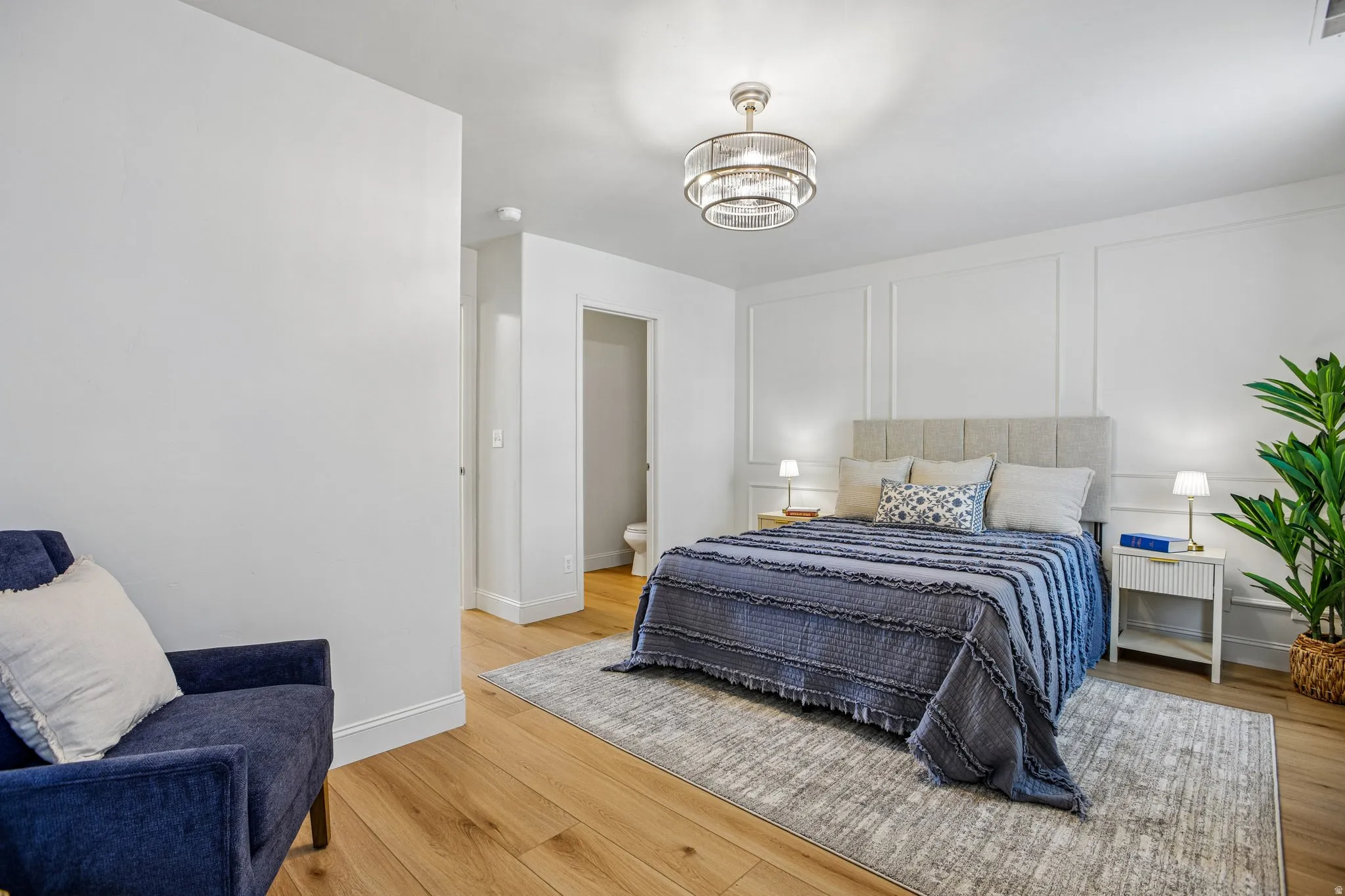 Bedroom featuring wood-finish flooring, a decorative paneled accent wall, and a contemporary semi-flush mount ceiling fixture