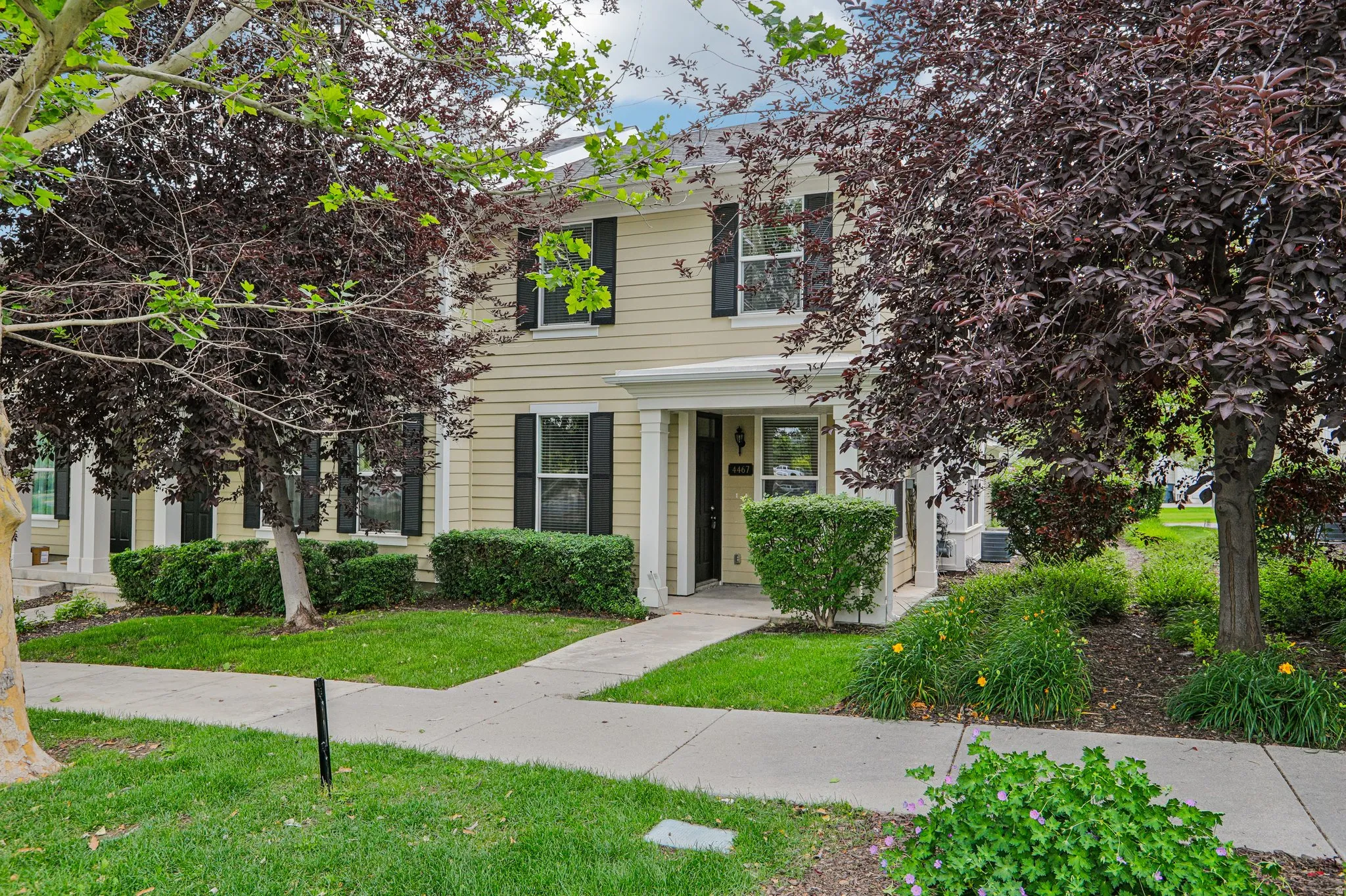 Two-story residence featuring light-colored siding, black window shutters, and a covered entry