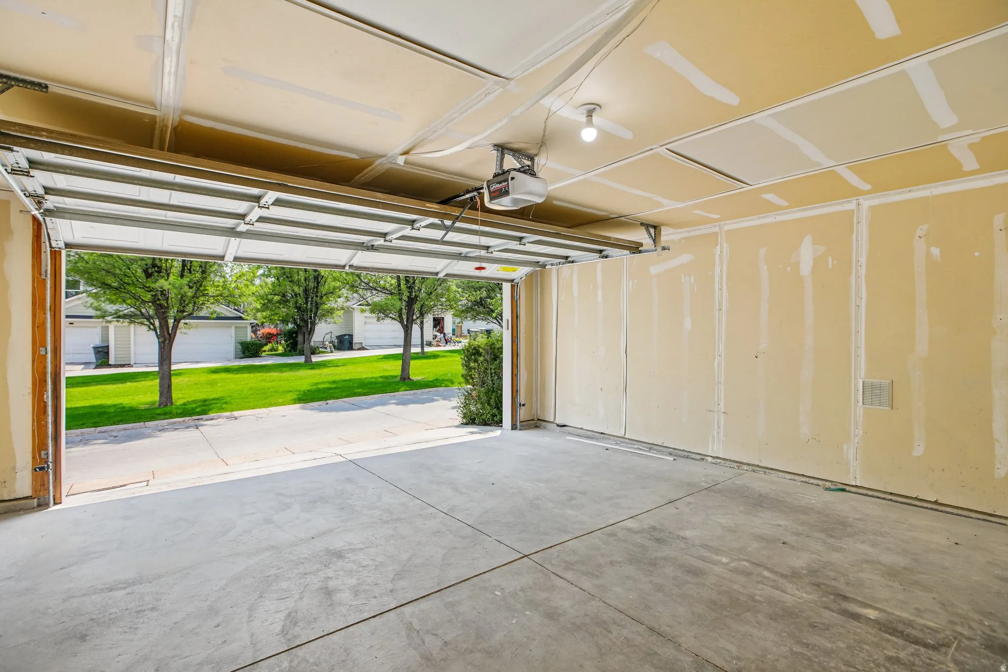 Spacious garage featuring a concrete floor, an overhead garage door, and visible drywall