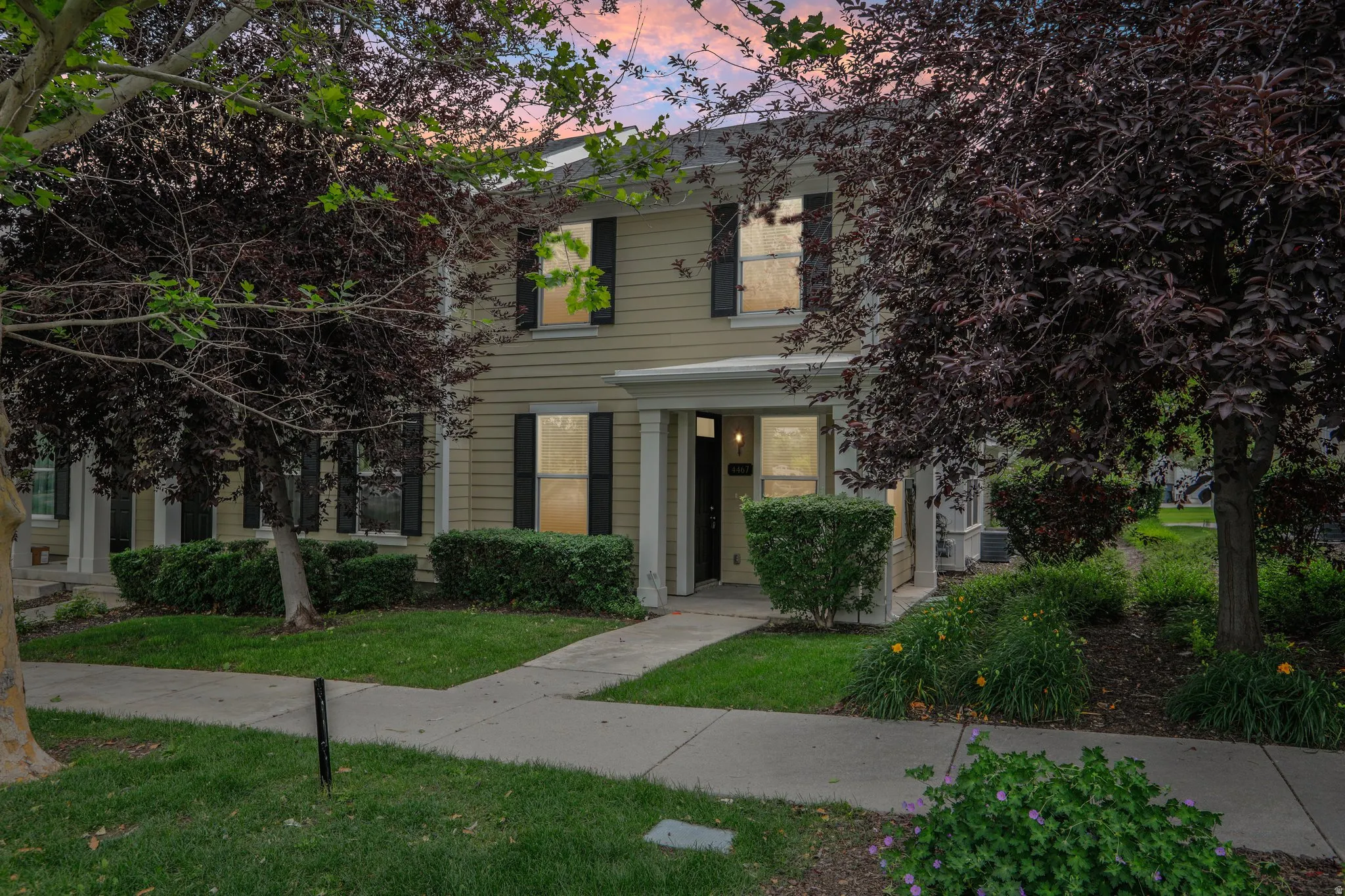 Two-story residence featuring light-colored siding and black window shutters
