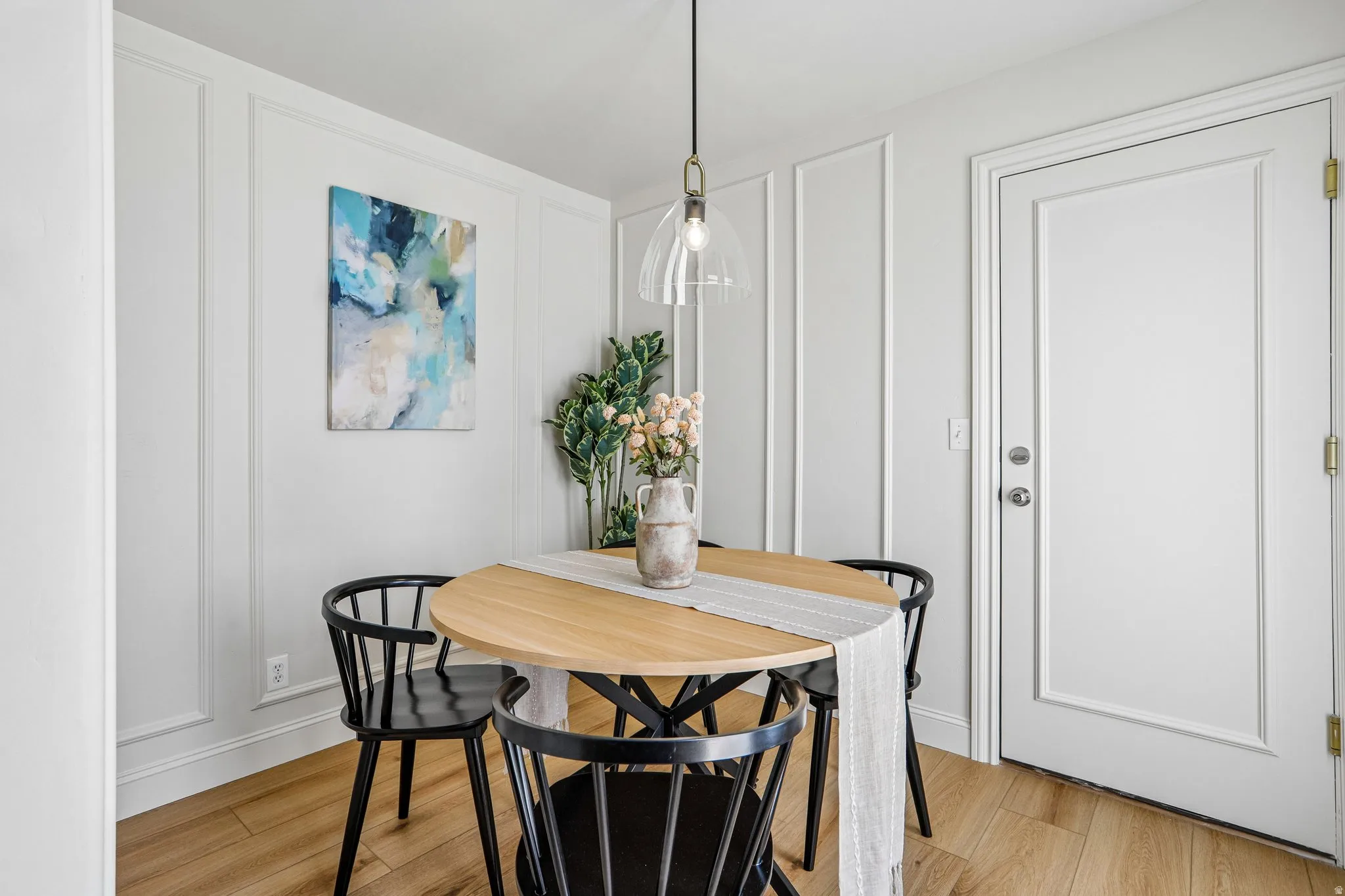 Dining area featuring wainscoting, wood-finish flooring, and a modern pendant light fixture