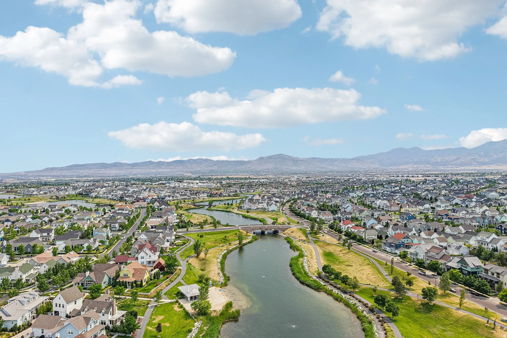 Expansive community featuring numerous single-family residences, a winding waterway, multiple bridges, and green spaces