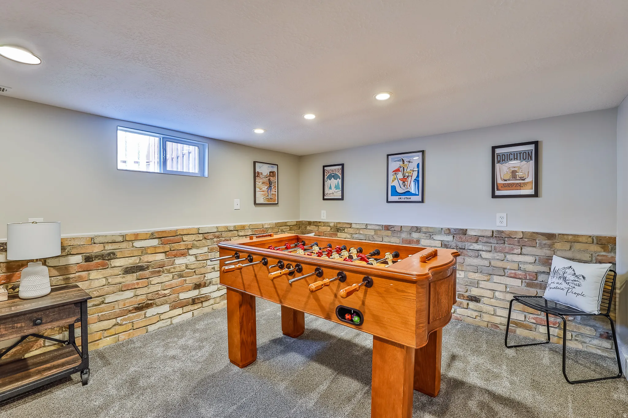 Finished interior space with a window, recessed lighting, carpet flooring, and a brick-finish accent wall