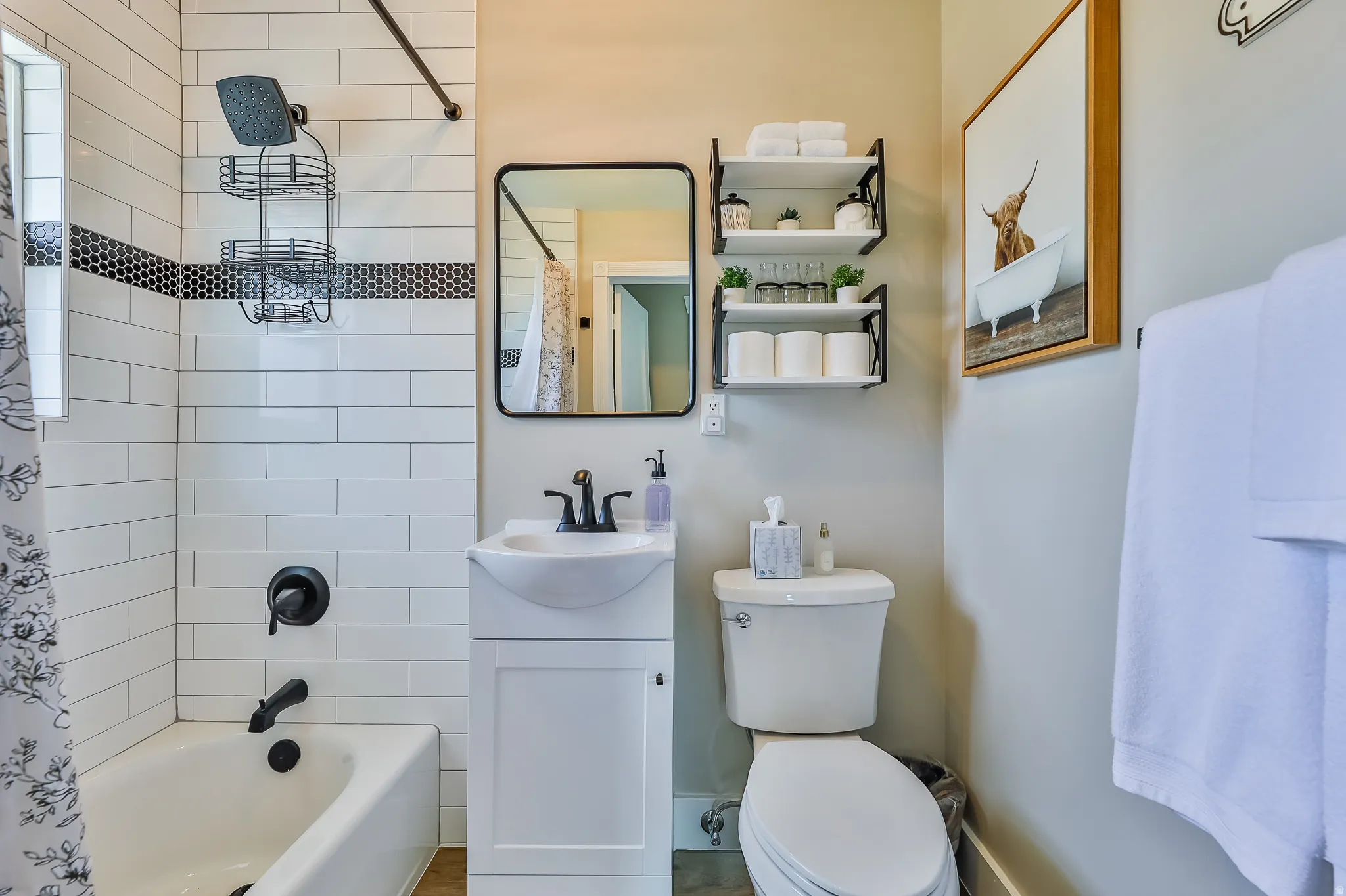 Bathroom featuring white subway tile surround with a black mosaic accent, black matte fixtures, and a white vanity with an integrated sink