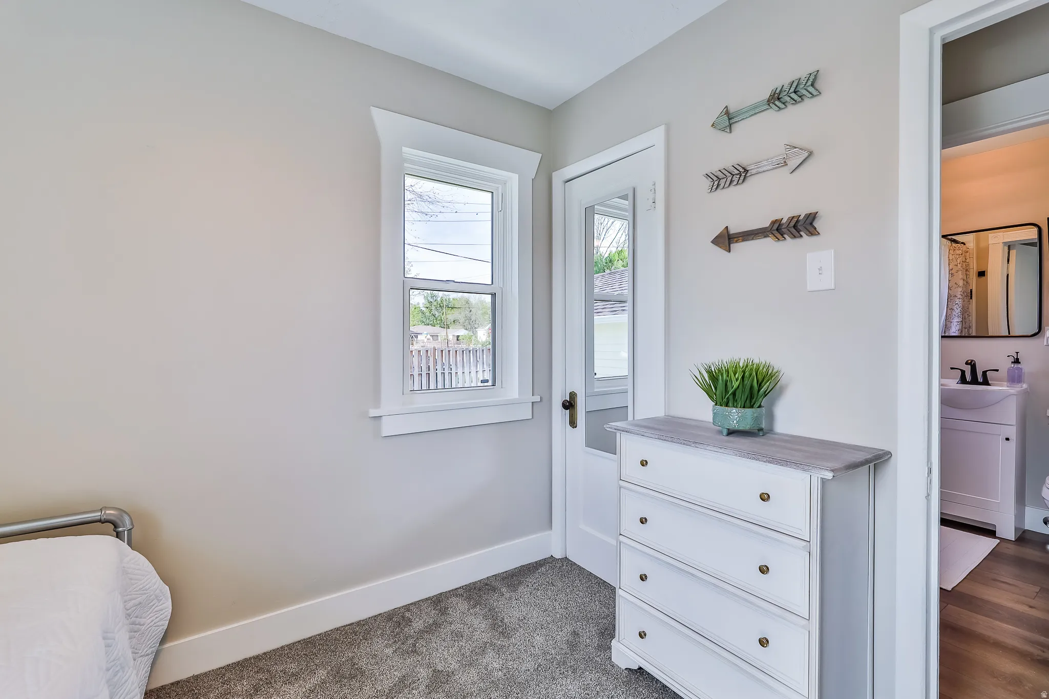 Light-toned walls with white trim, a single window, and plush gray carpeting