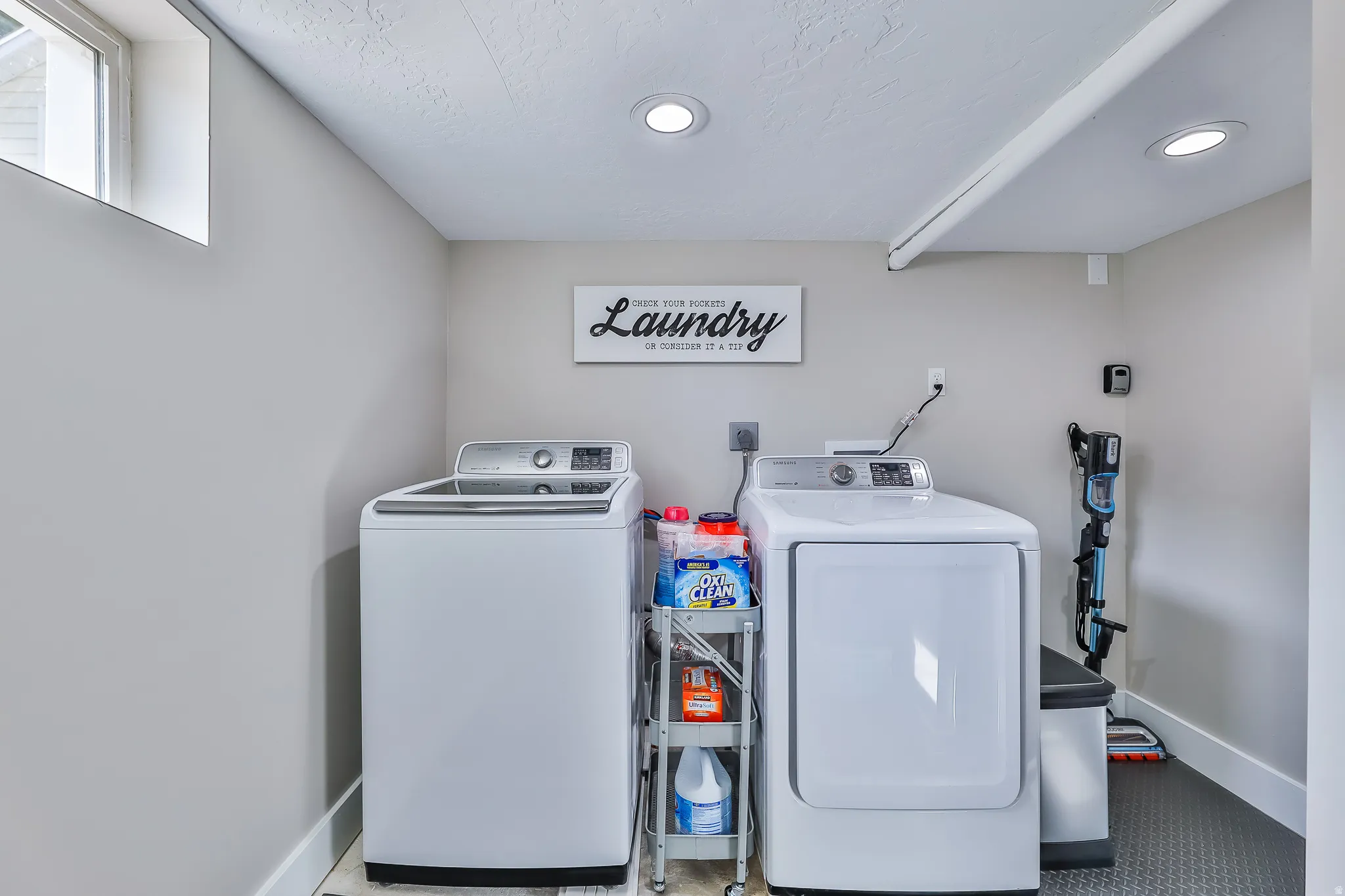 Dedicated laundry area featuring a window, recessed lighting, and durable flooring