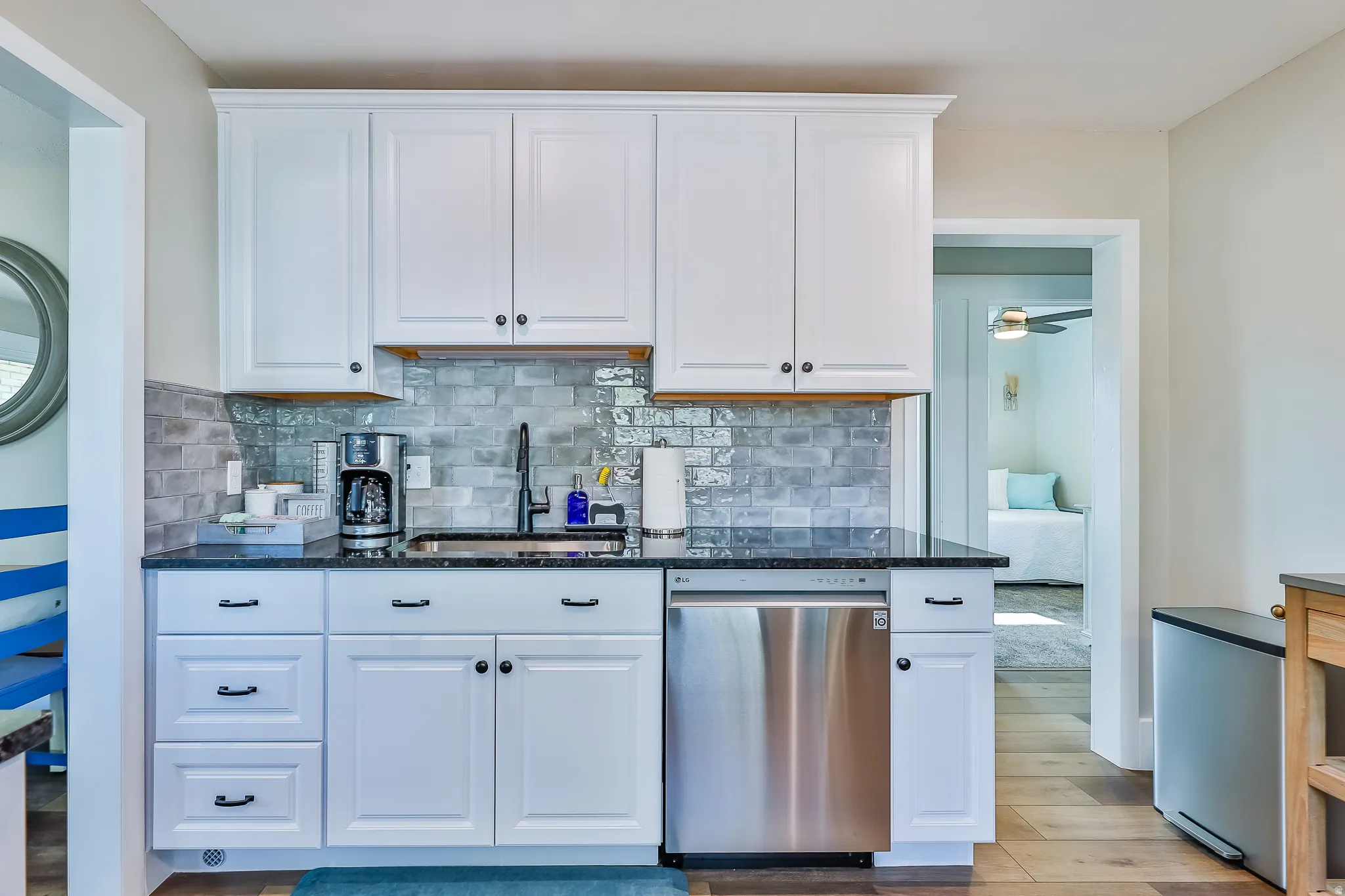 Compact kitchen featuring white cabinetry with dark hardware, granite-style countertops, and a subway tile backsplash
