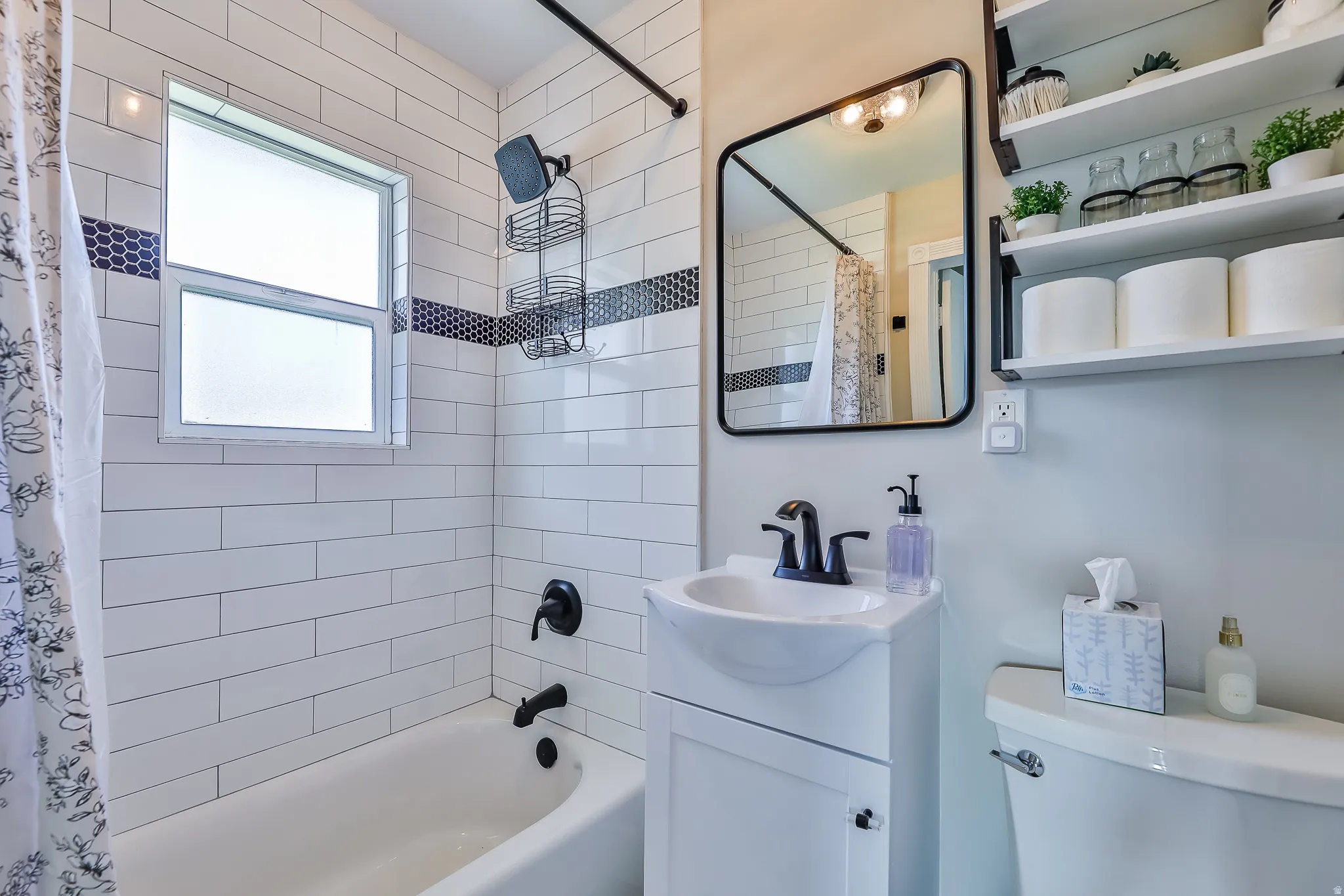 Bathroom featuring a white subway tile surround with a dark mosaic accent band
