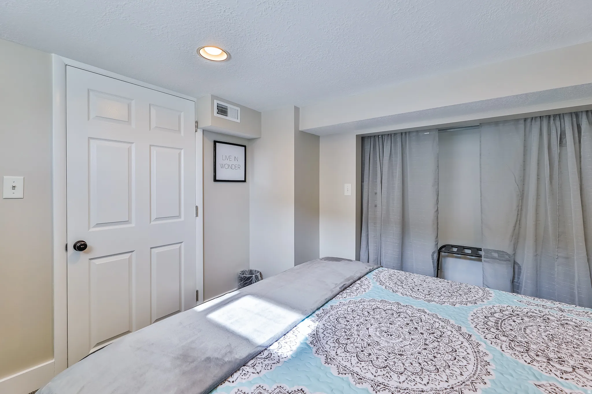 Recessed ceiling light illuminating a neutral-toned room with a white paneled door