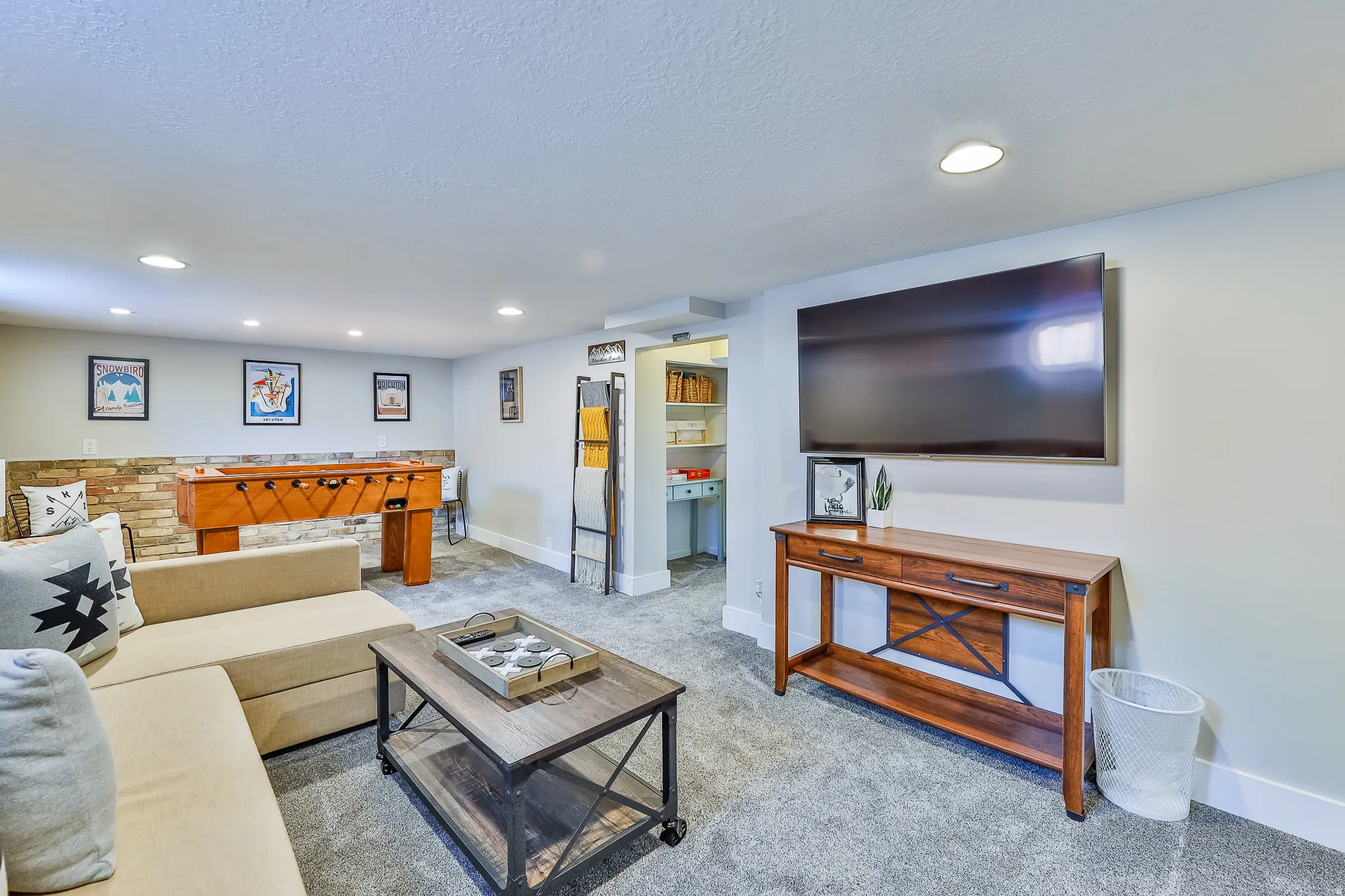 Spacious entertainment area featuring recessed lighting, gray carpeting, and a stone accent wall