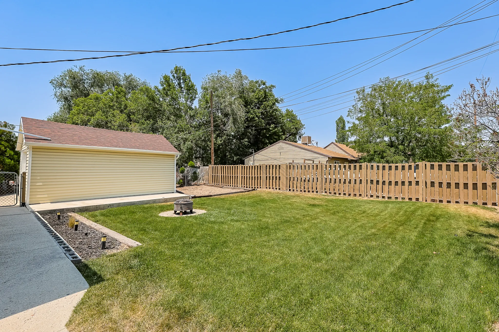 Expansive backyard featuring a manicured lawn, full wood privacy fence, and a detached garage with vinyl siding and a shingled roof