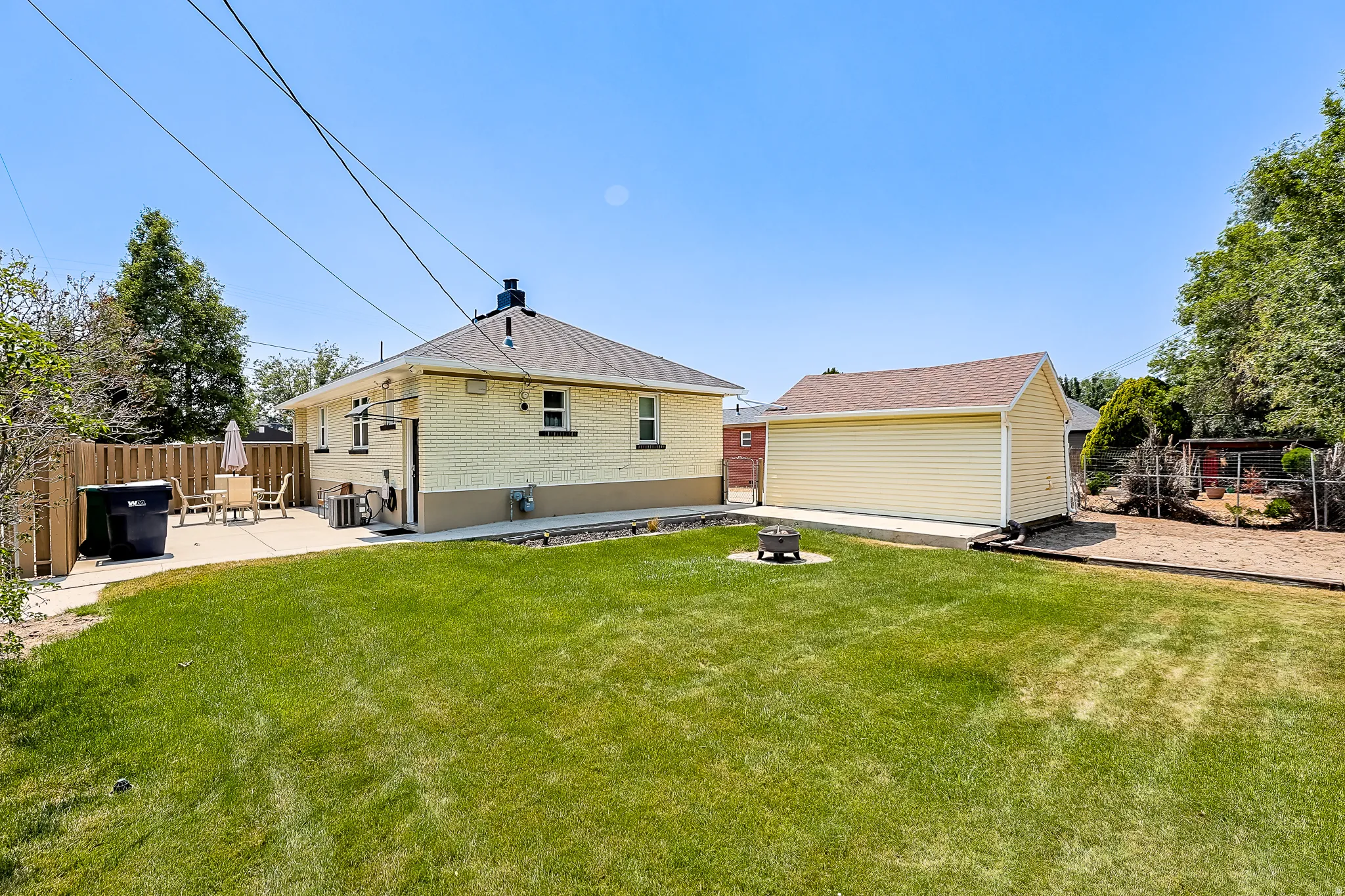 Expansive backyard featuring a manicured lawn, concrete patio, and a detached garage with siding