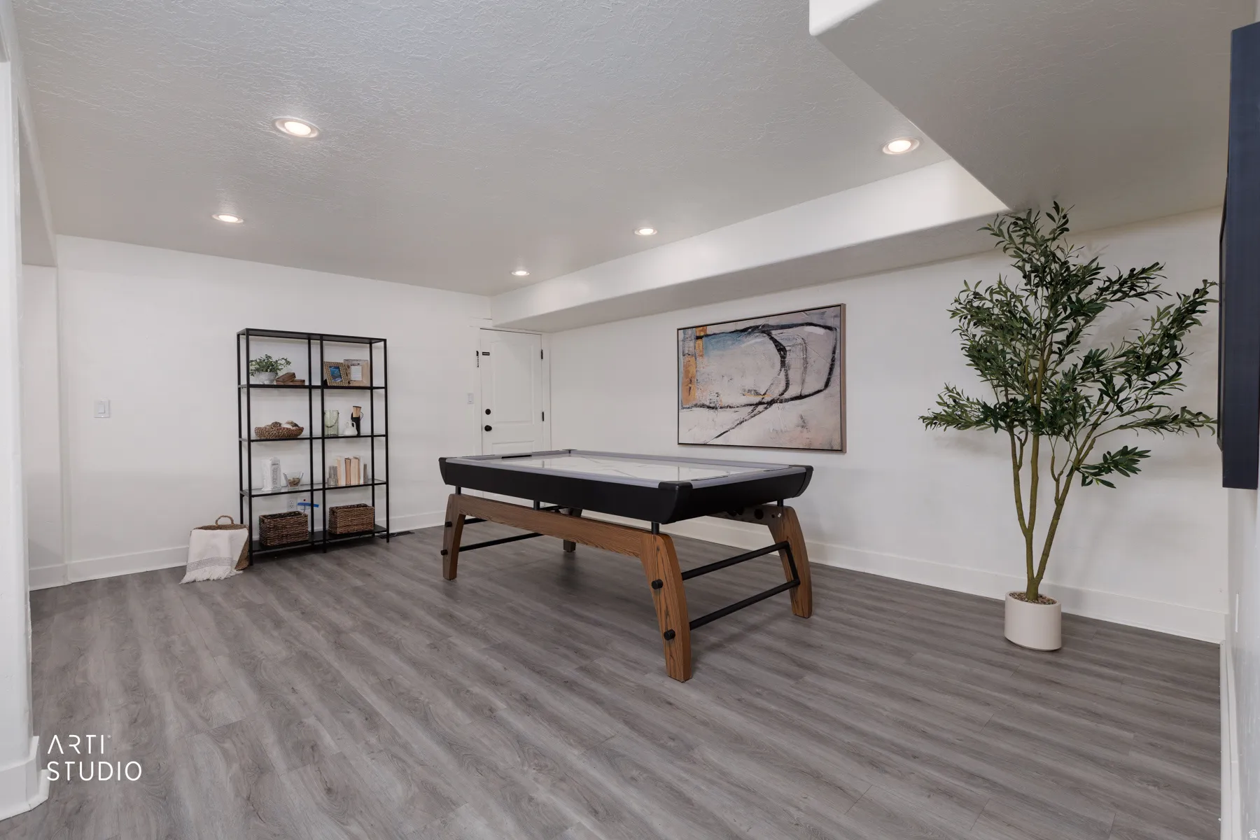 Spacious recreation area featuring wood-finish flooring, white walls, and recessed lighting