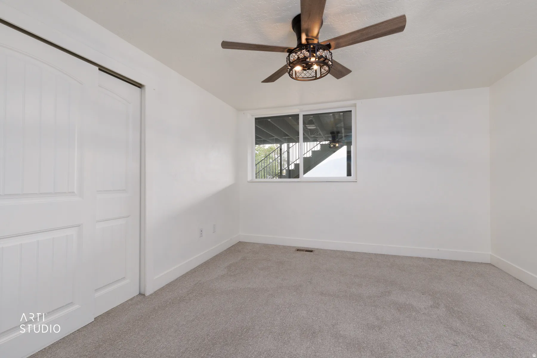 Bedroom featuring plush grey carpeting, a large window, and a ceiling fan with integrated lighting