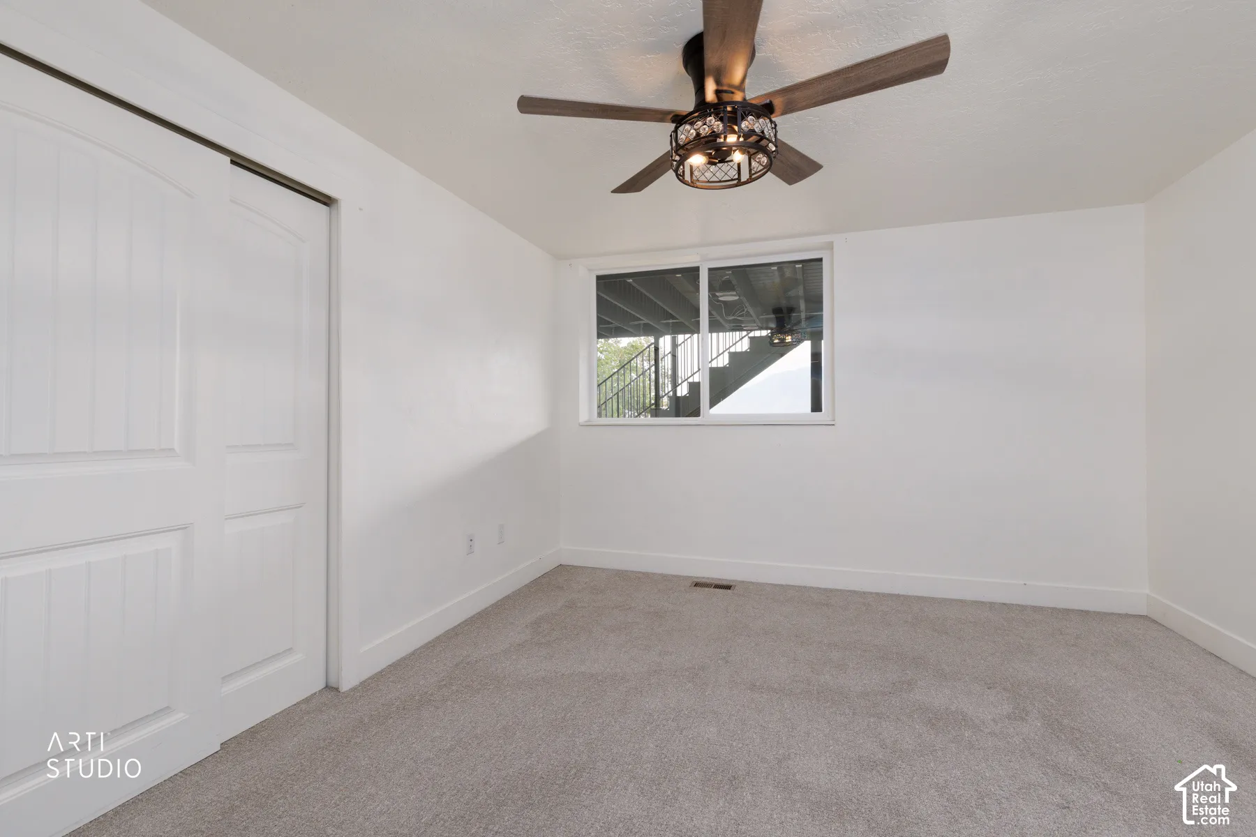 Bedroom featuring plush grey carpeting, a large window, and a ceiling fan with integrated lighting
