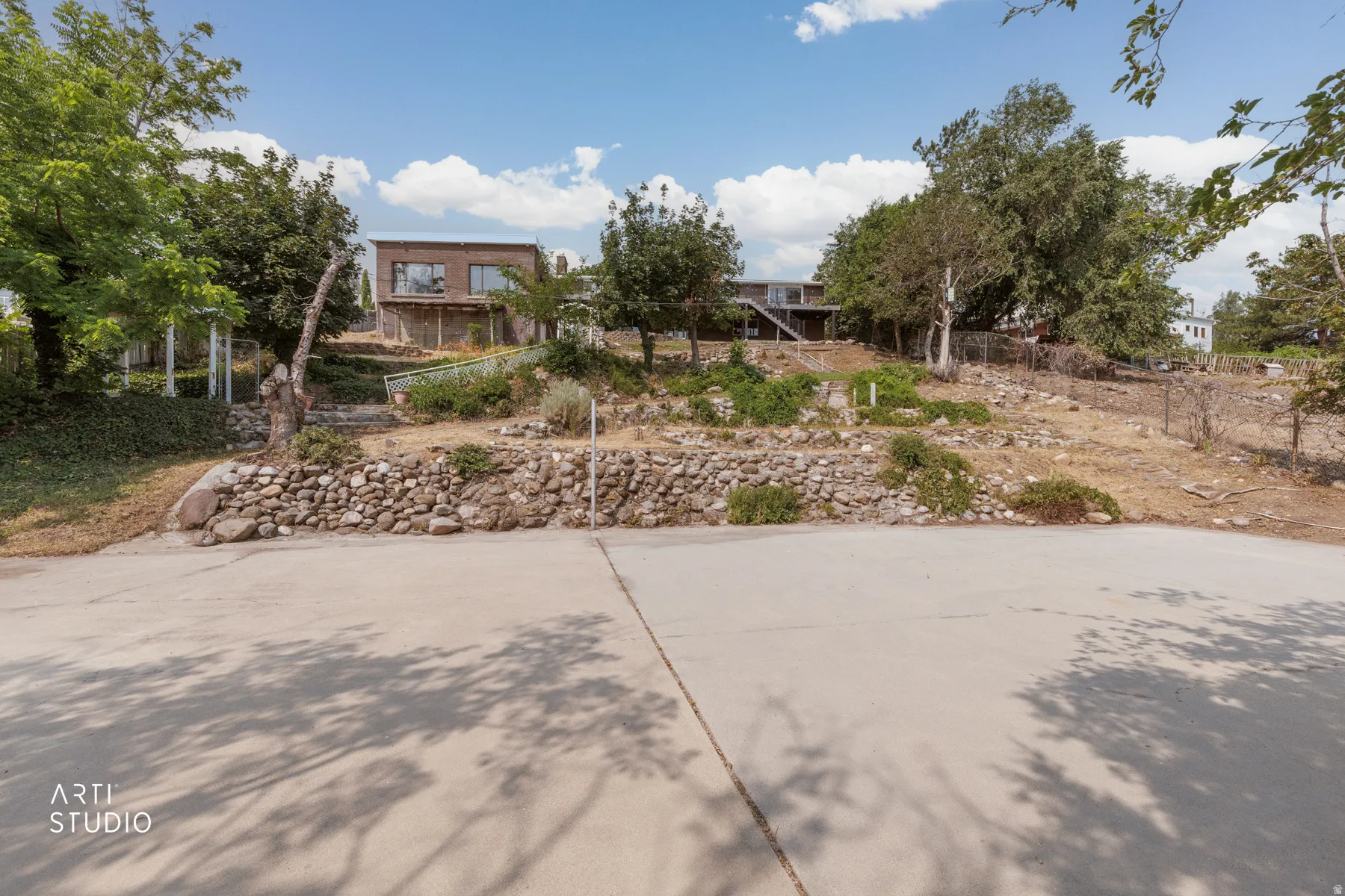Terraced property with natural landscaping, featuring a stone retaining wall and mature trees
