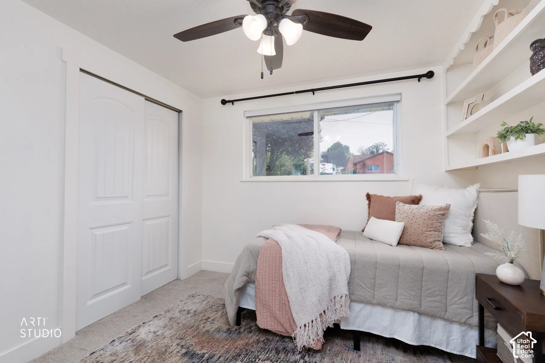 Room featuring a window, built-in shelving, a ceiling fan, and sliding closet doors
