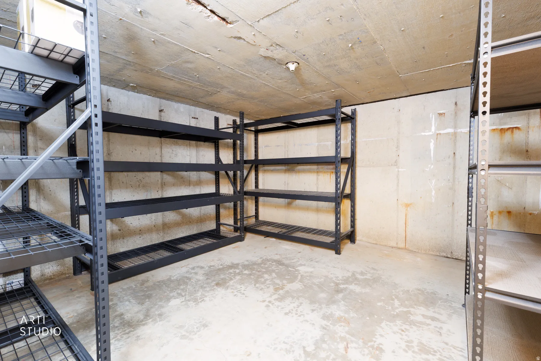 Concrete-walled storage area featuring multiple metal shelving units, offering extensive organizational capacity