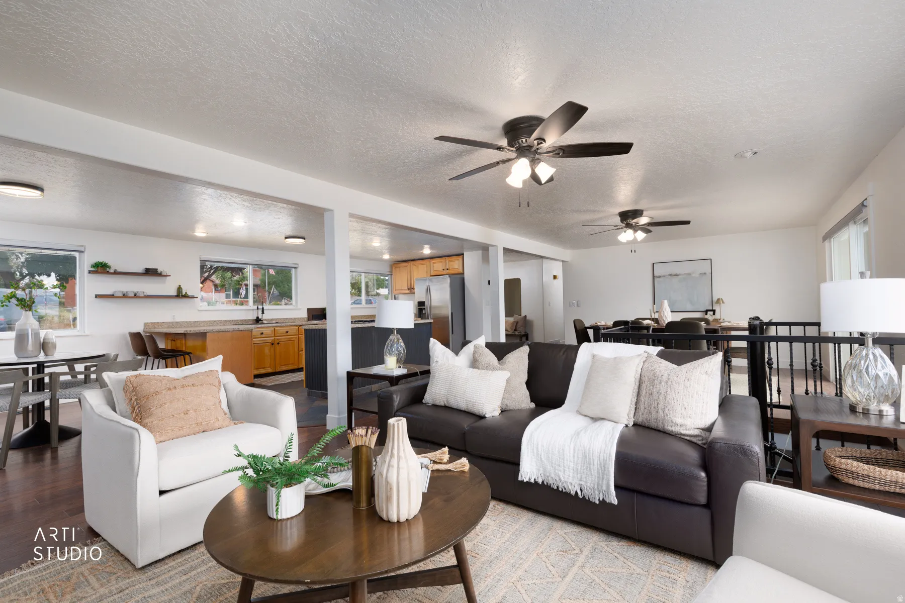 Expansive open-concept living area featuring dark wood-finish flooring, multiple ceiling fans, and recessed lighting