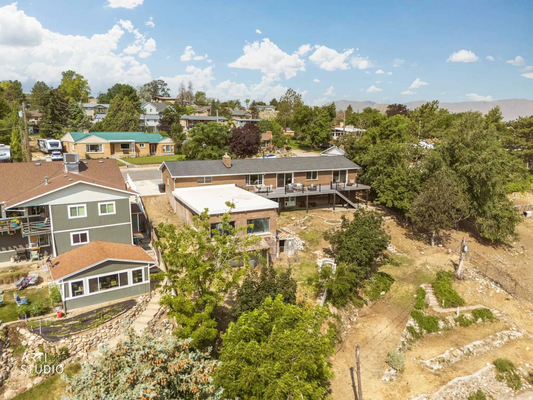 Multi-level residence featuring a brick and siding exterior, multiple elevated decks with railings, and a lower-level sunroom