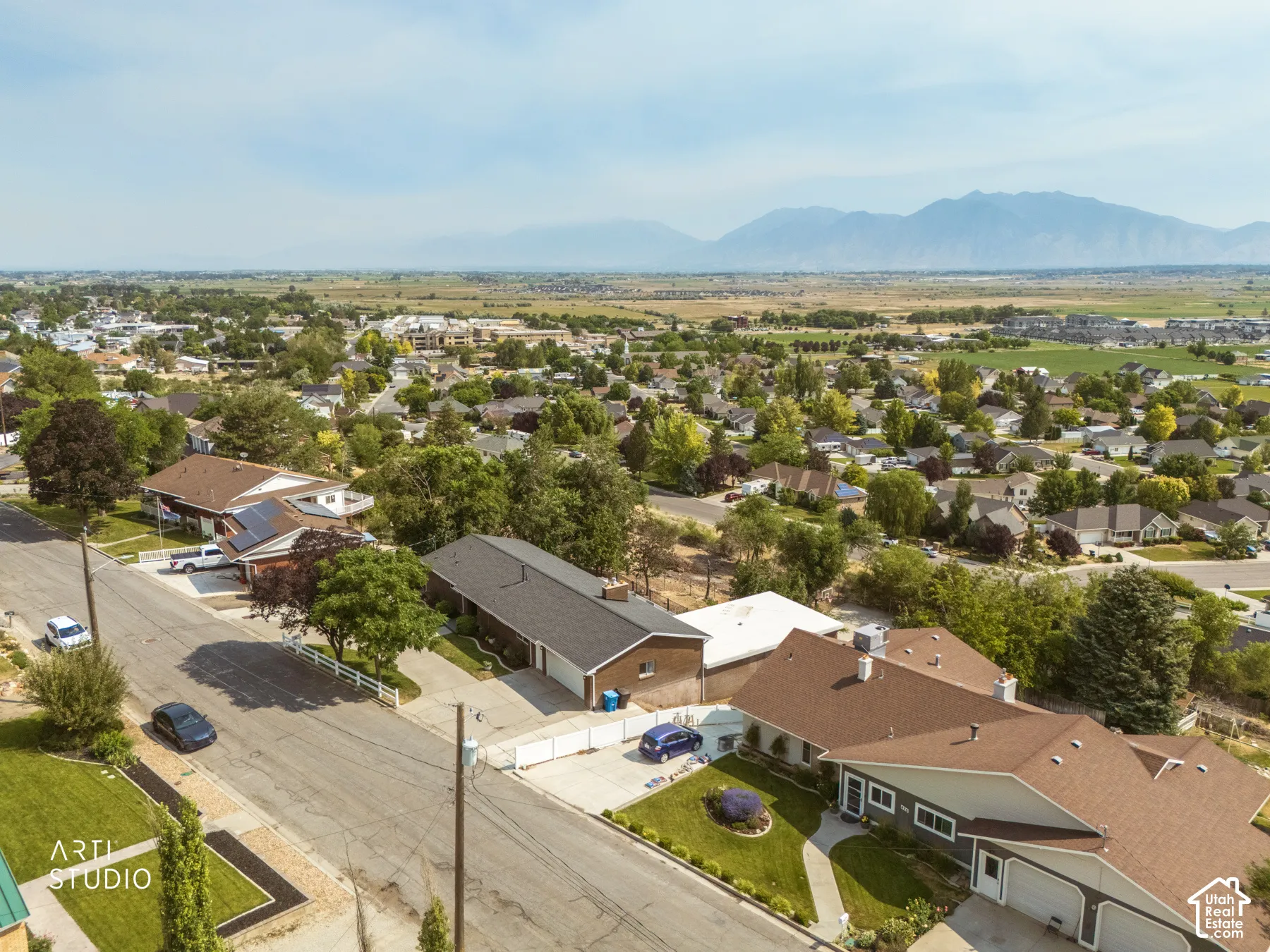 Expansive residential community featuring mature trees, mountain backdrop, and multiple single-family residences with attached garages and well-maintained landscaping