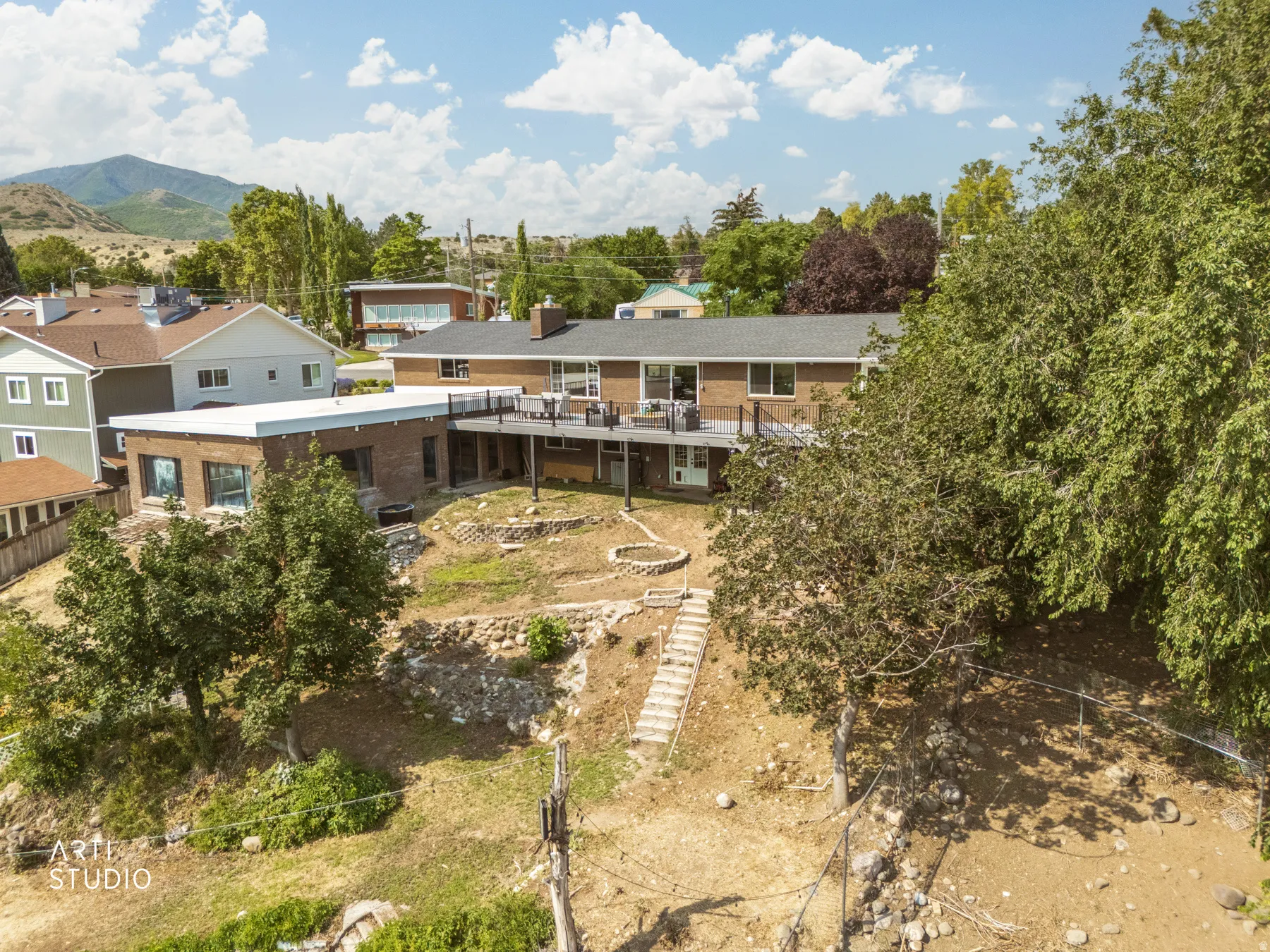 Brick exterior with a multi-level deck, featuring a terraced backyard and hillside landscaping