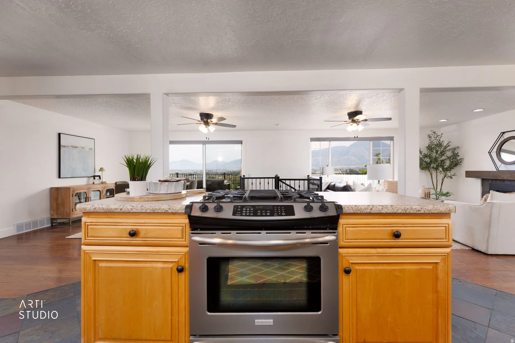 Kitchen island featuring a stainless steel range, light wood-finish cabinetry, and a light-toned countertop