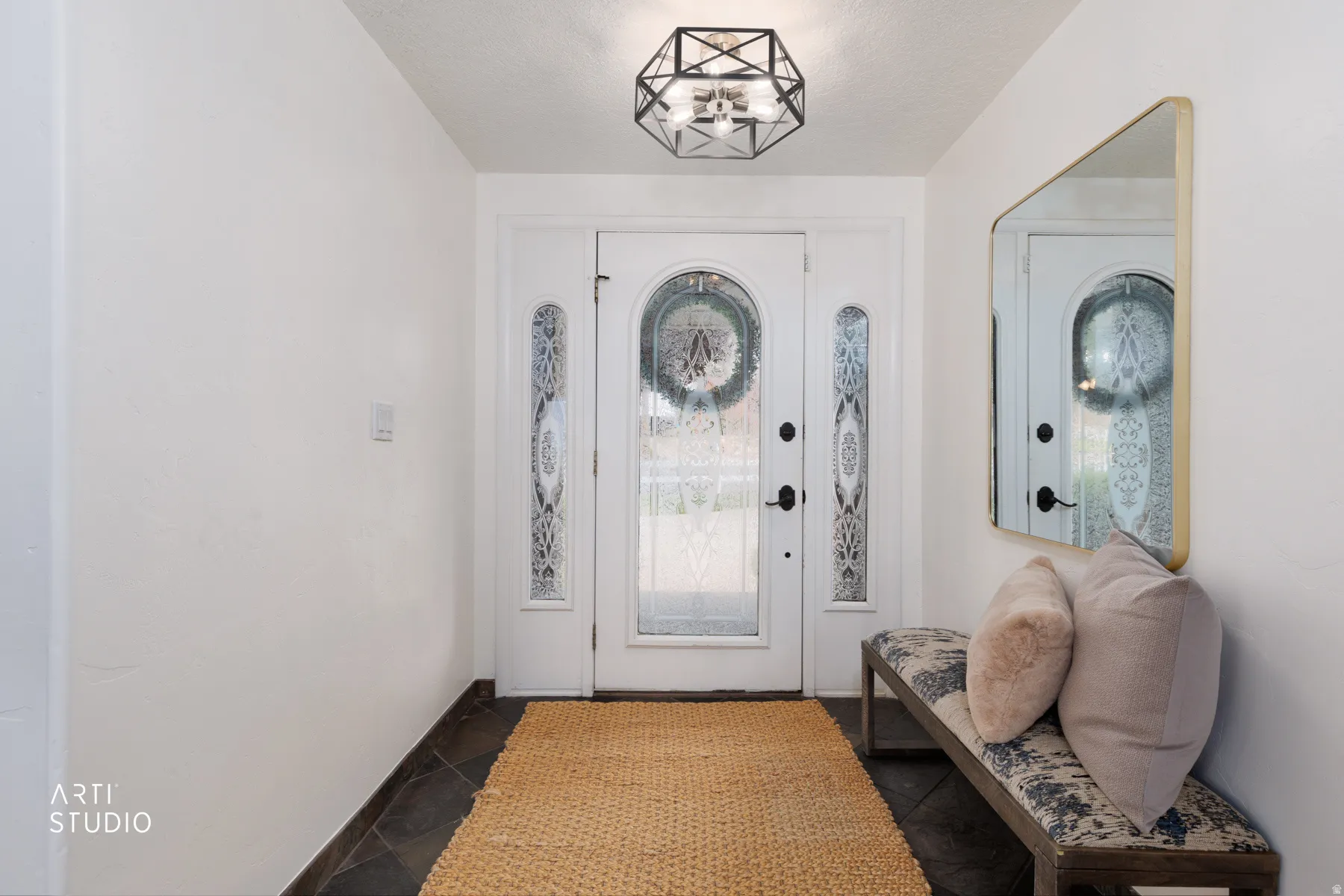 Entryway featuring a decorative front door with arched glass and sidelights, dark tile flooring, and a contemporary geometric flush-mount light fixture