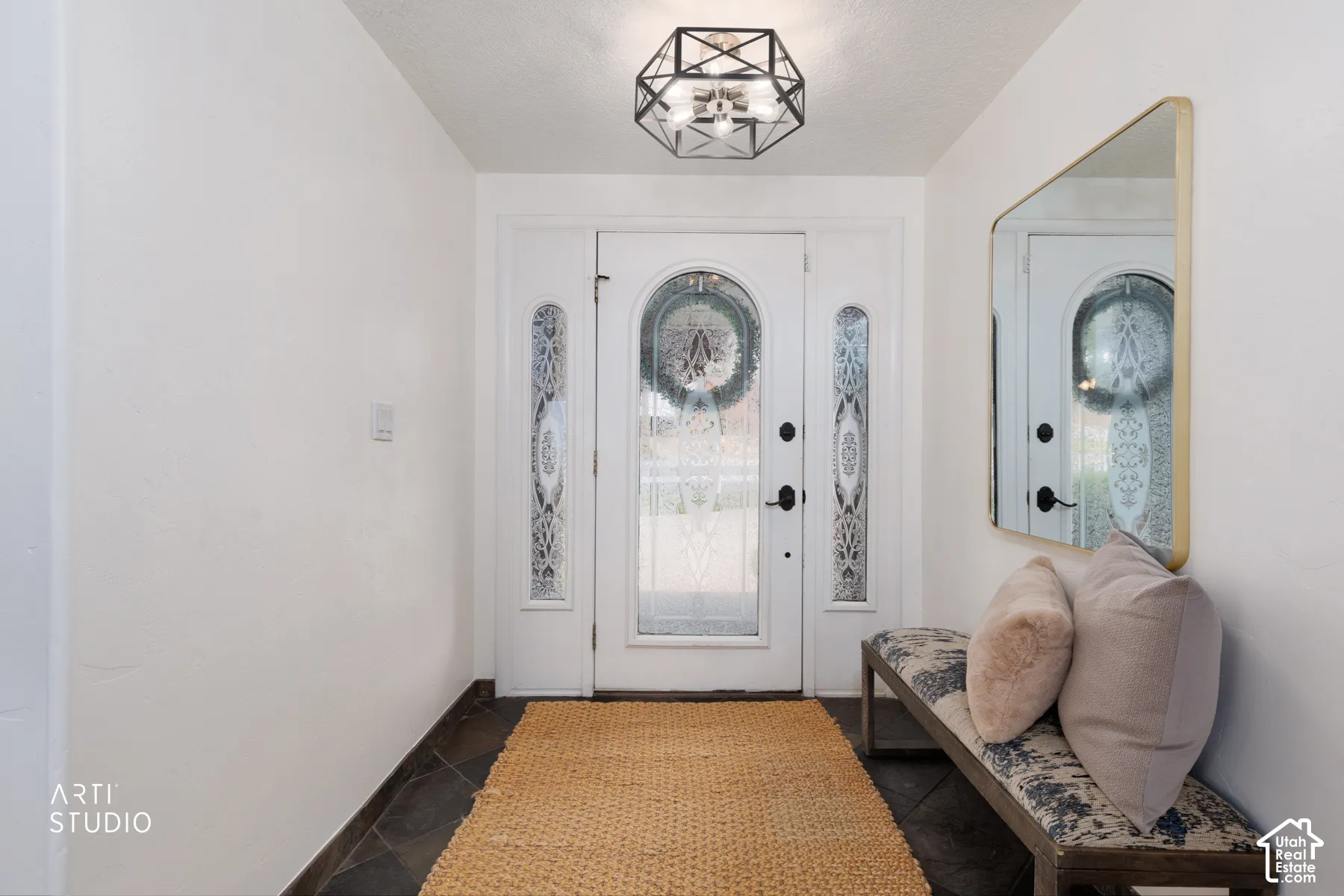 Entryway featuring a decorative front door with arched glass and sidelights, dark tile flooring, and a contemporary geometric flush-mount light fixture