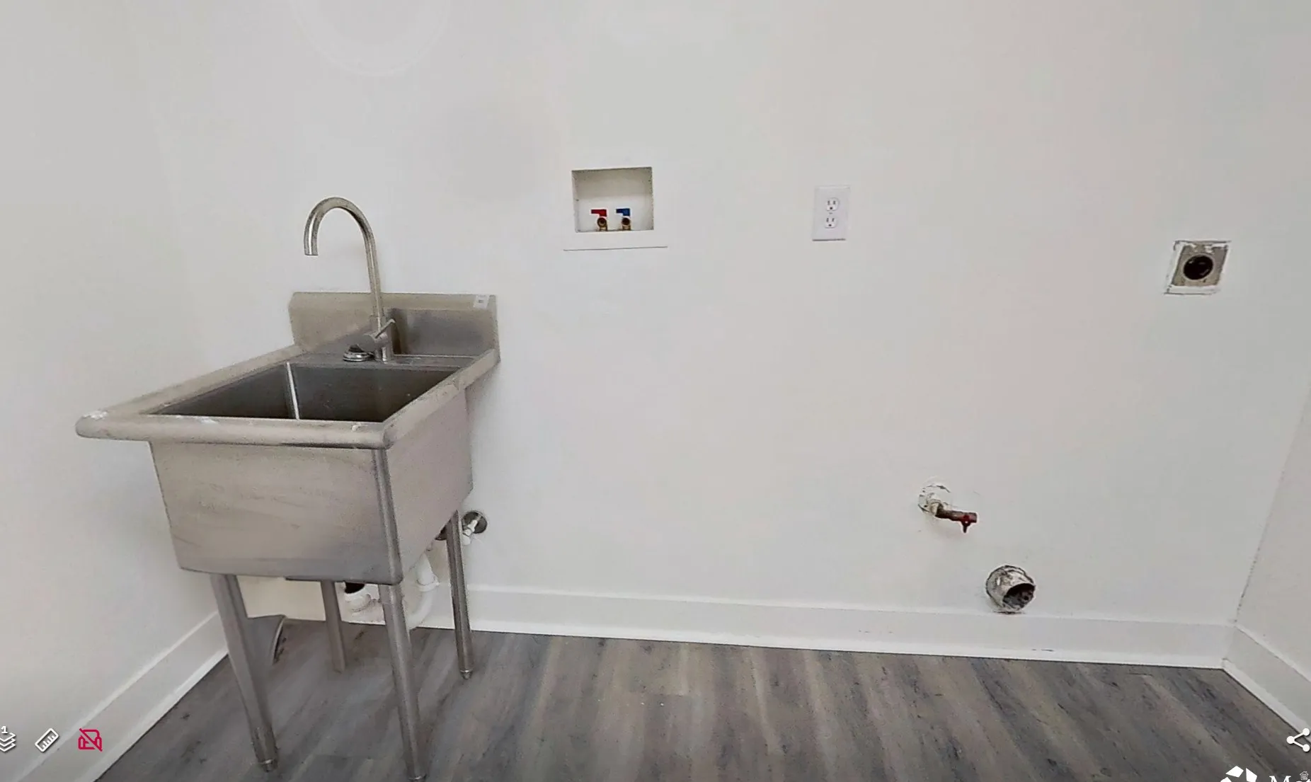 Utility room featuring a stainless steel washbasin with a gooseneck faucet, white walls, and wood-finish flooring