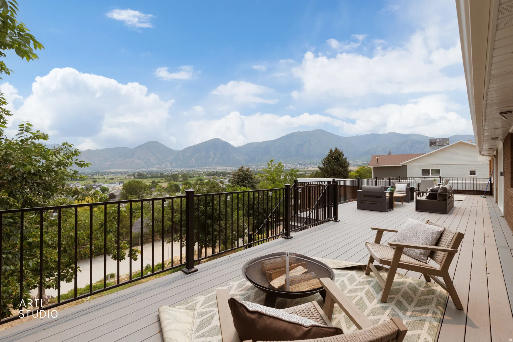 Expansive outdoor deck featuring composite decking, black metal railings, and a wide mountain backdrop