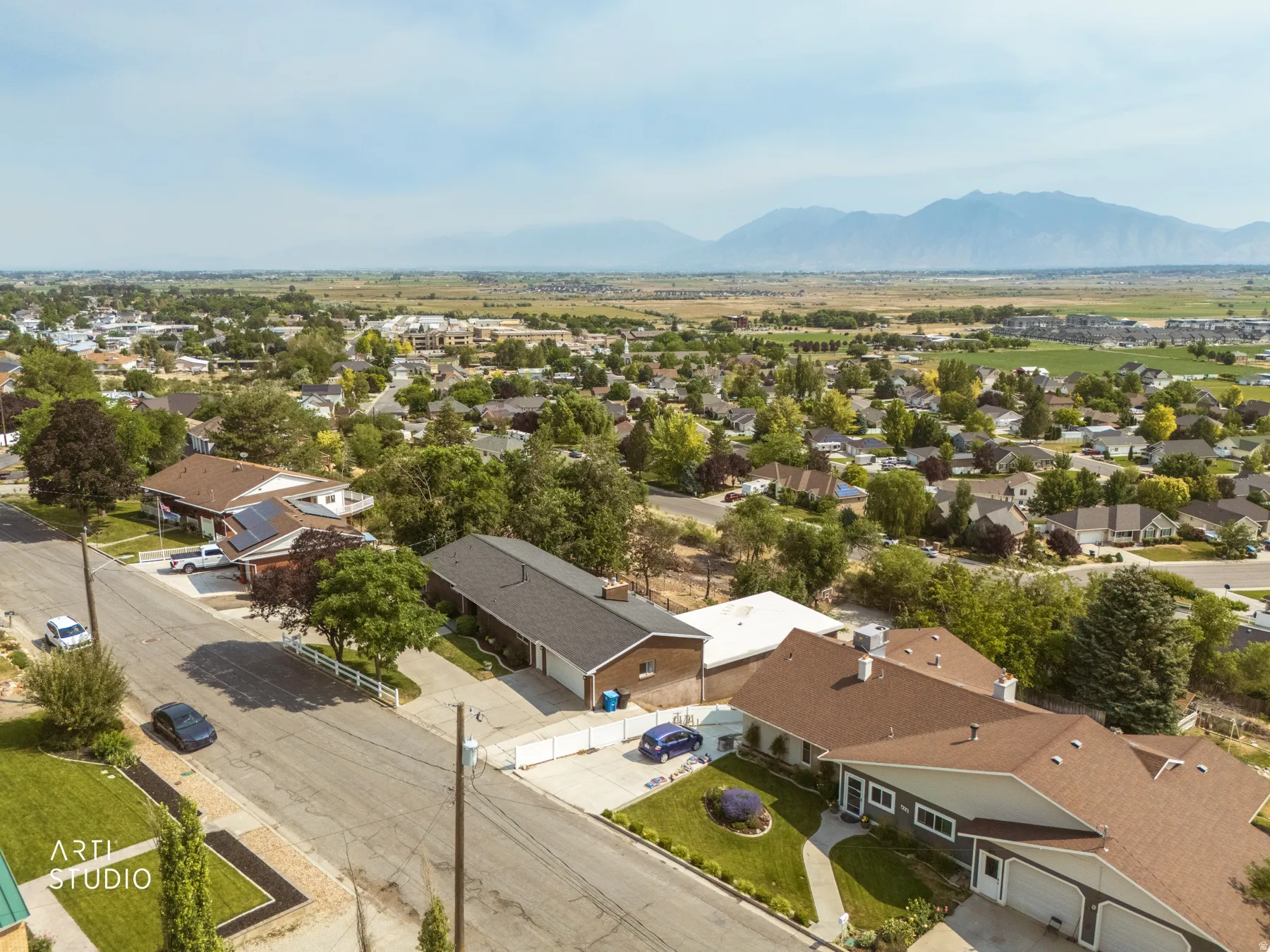 Expansive residential community featuring mature trees, mountain backdrop, and multiple single-family residences with attached garages and well-maintained landscaping