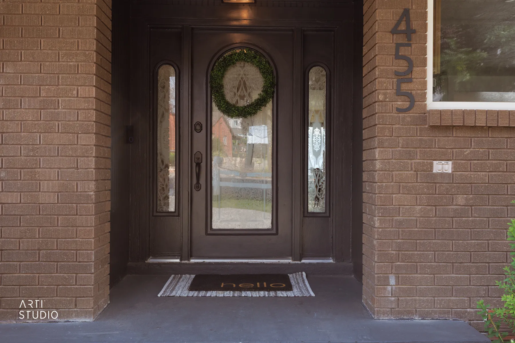 Brick exterior featuring a dark entry door with decorative glass inserts and sidelights